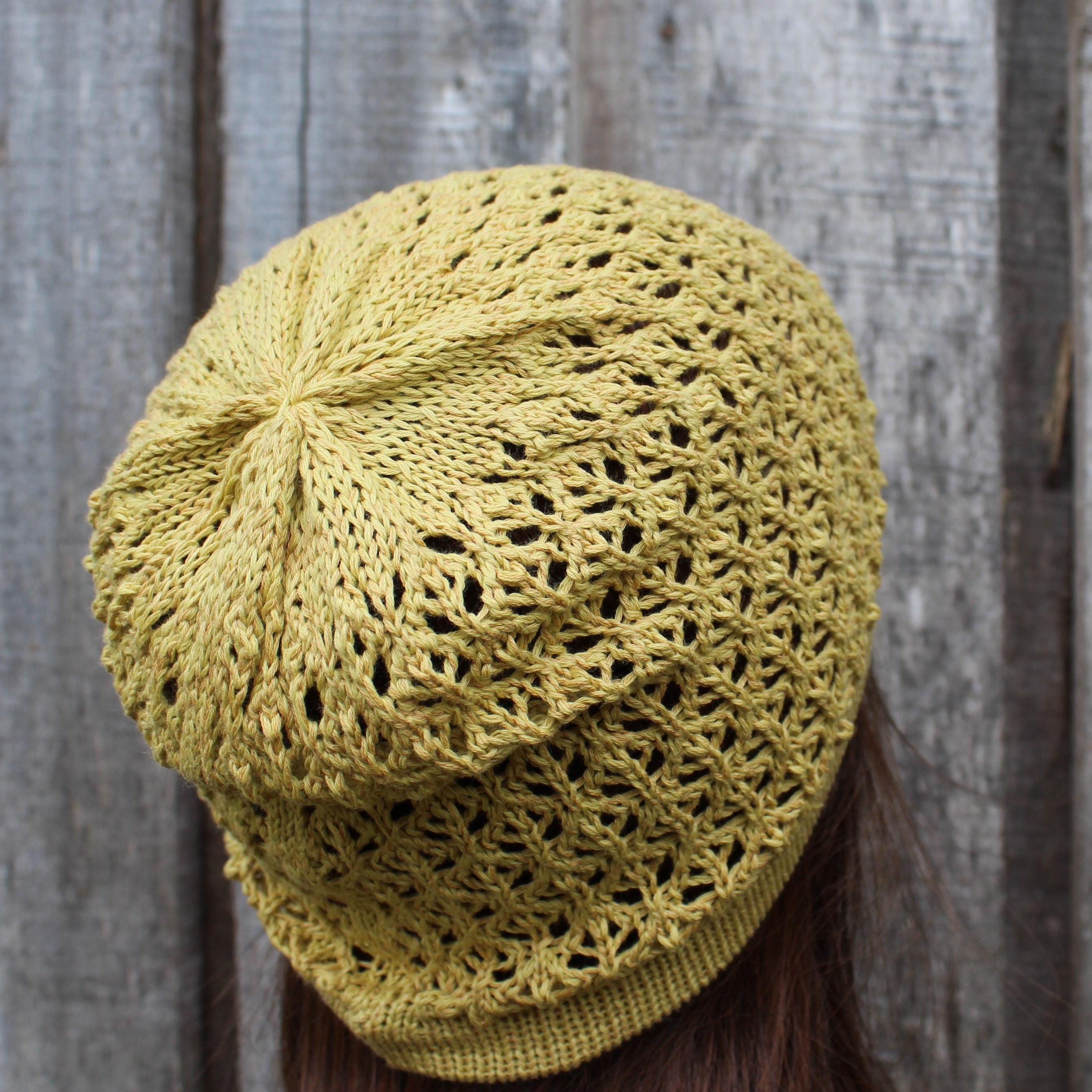 Yellow knitted hat worn by a person against a wooden fence background