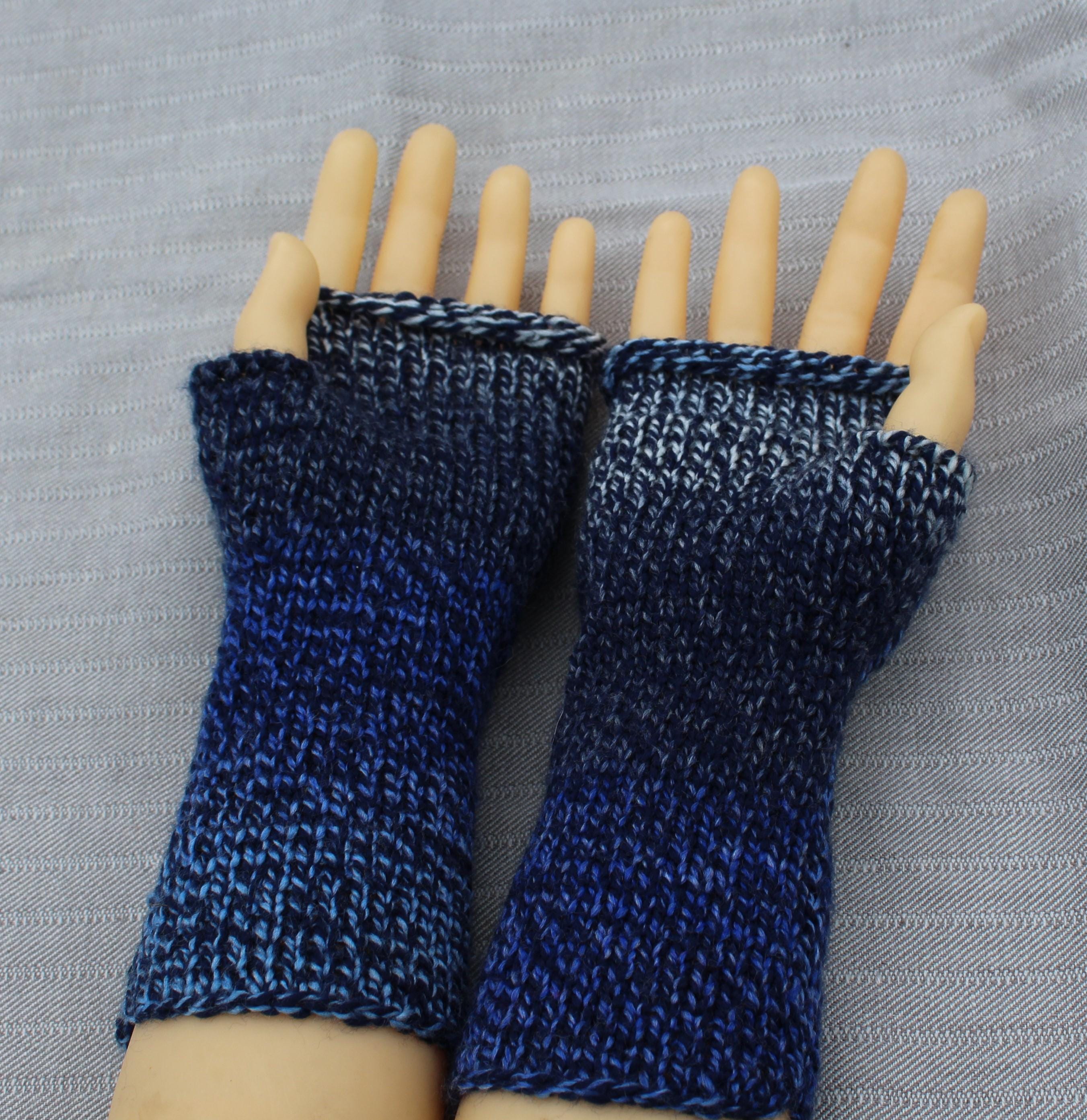 Blue knitted fingerless gloves on a mannequin hand against a gray background