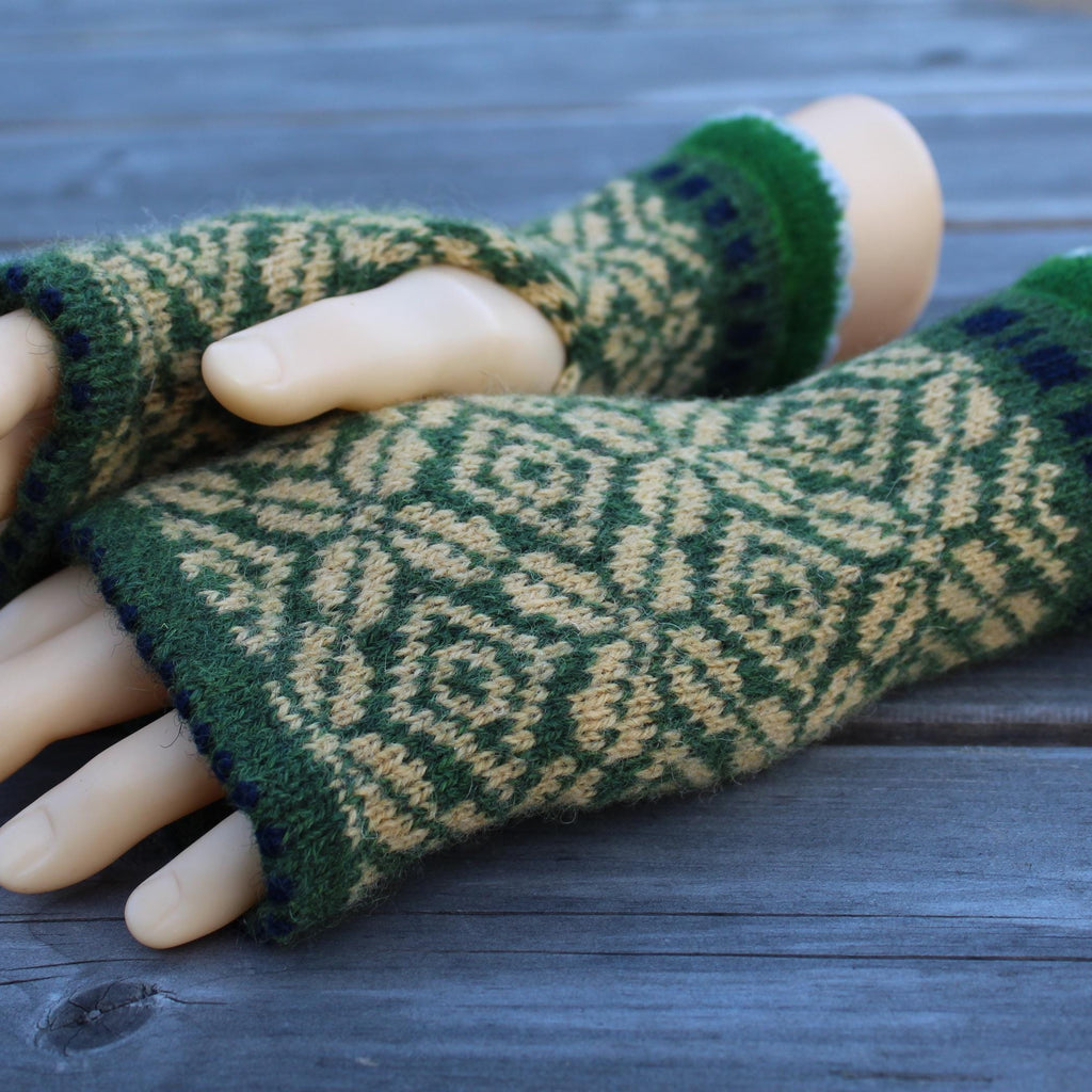 Knitted green and yellow half mittens on a wooden surface