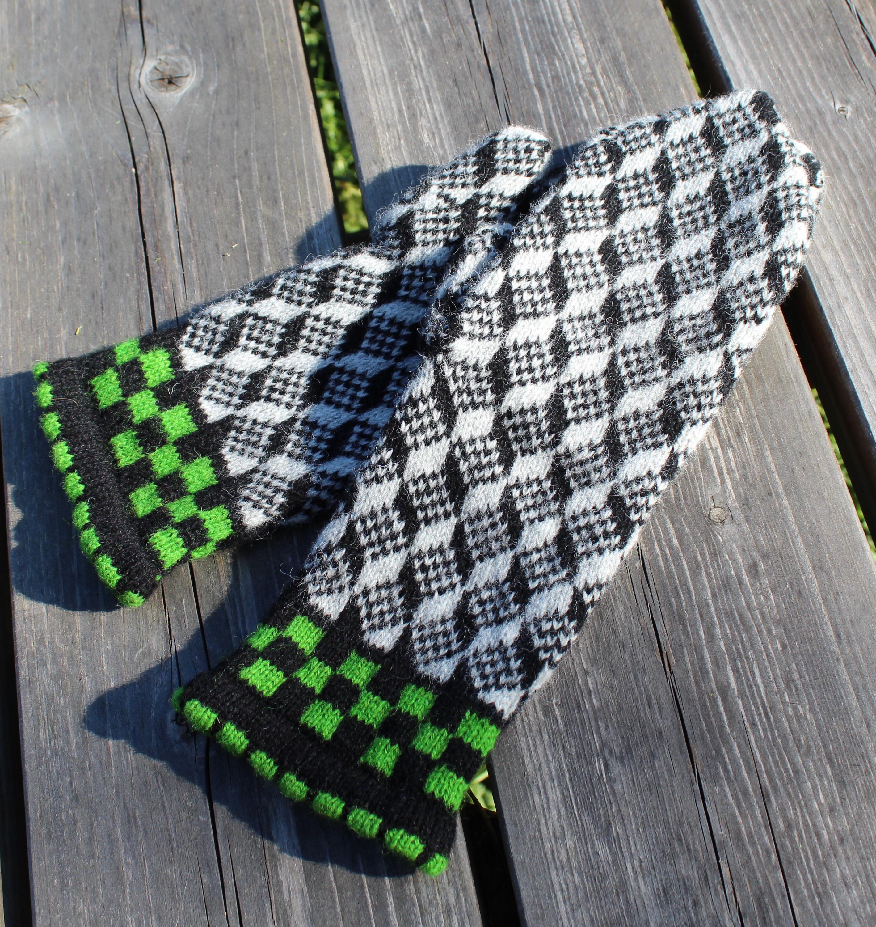 Pair of black, white, and green checkered gloves on a wooden surface