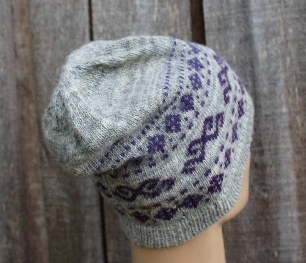 Gray knit hat with purple pattern on a wooden background
