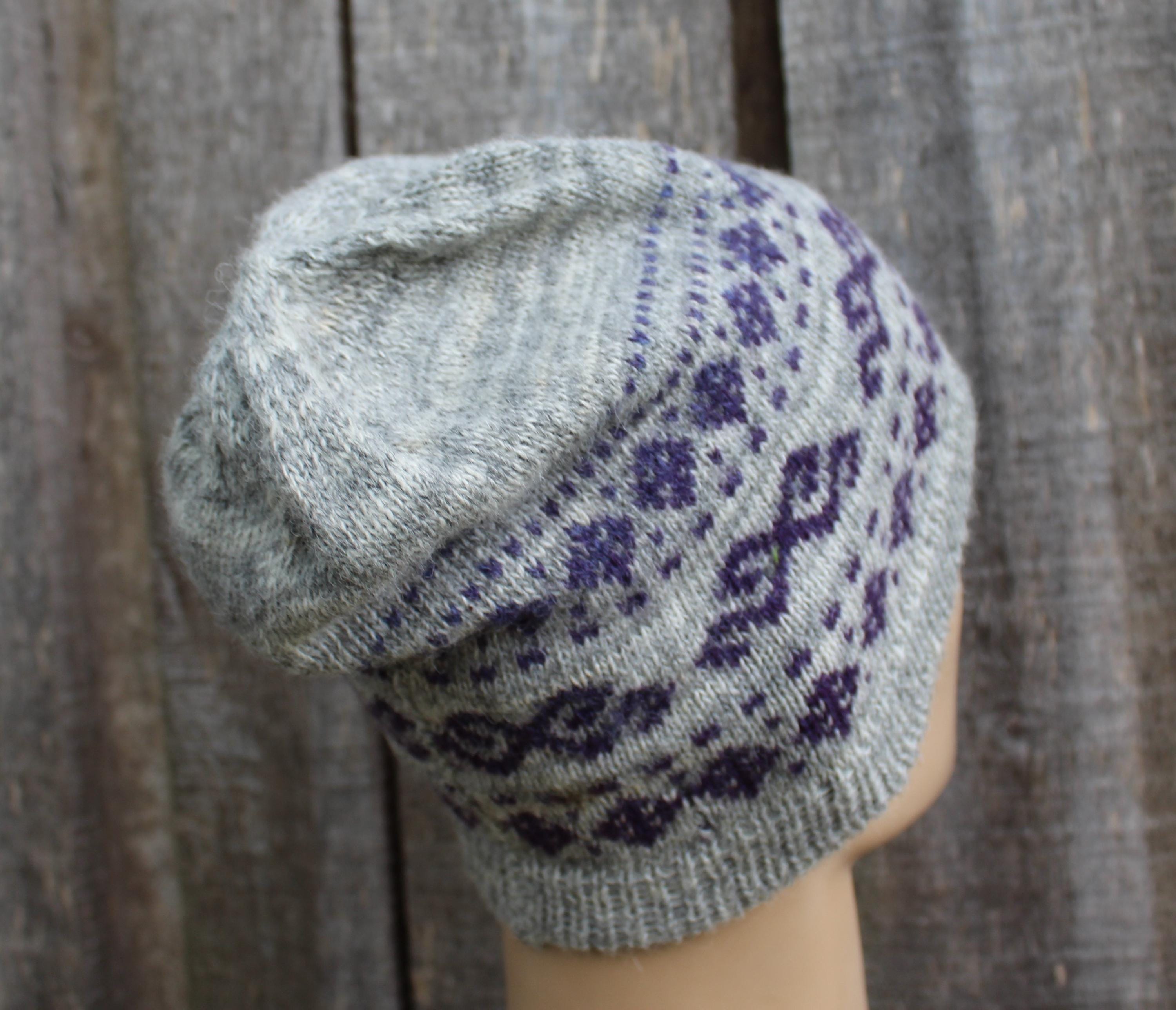 Gray knit hat with purple pattern on a wooden background