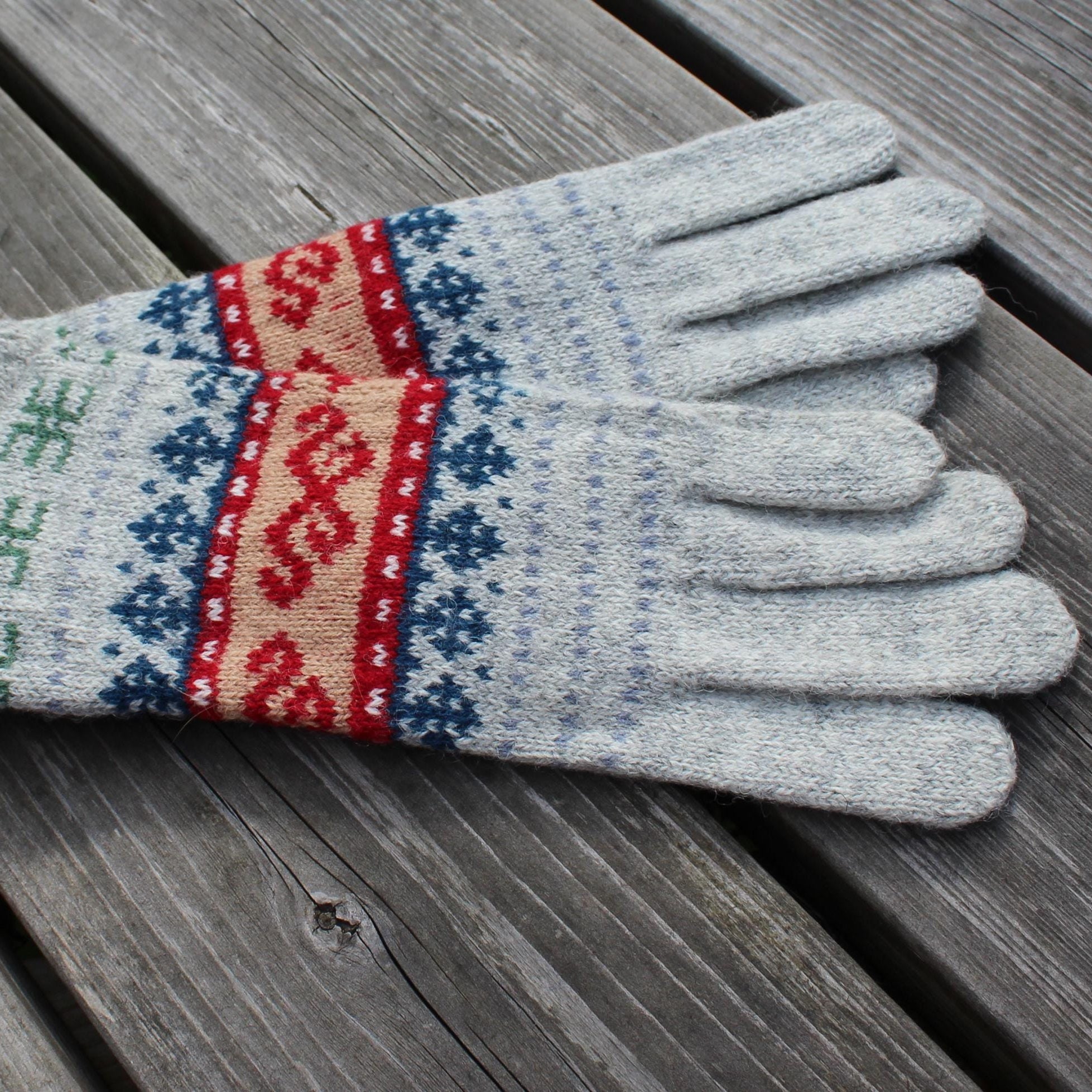 Gray knitted glove with colorful pattern on a wooden surface