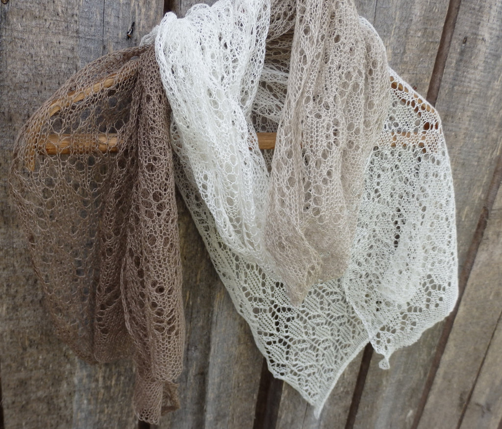 lace shawls, one brown and one white, draped over a wooden surface.