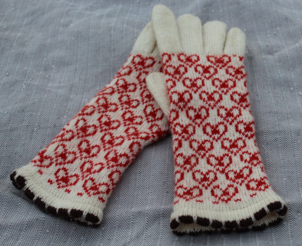 Pair of gloves with red and white pattern on a gray fabric background