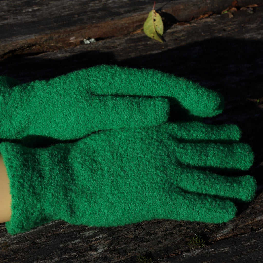 Green warm gloves on a wooden surface