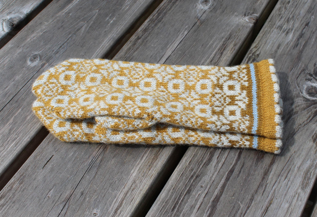 Knitted mitten with a geometric pattern on a wooden surface
