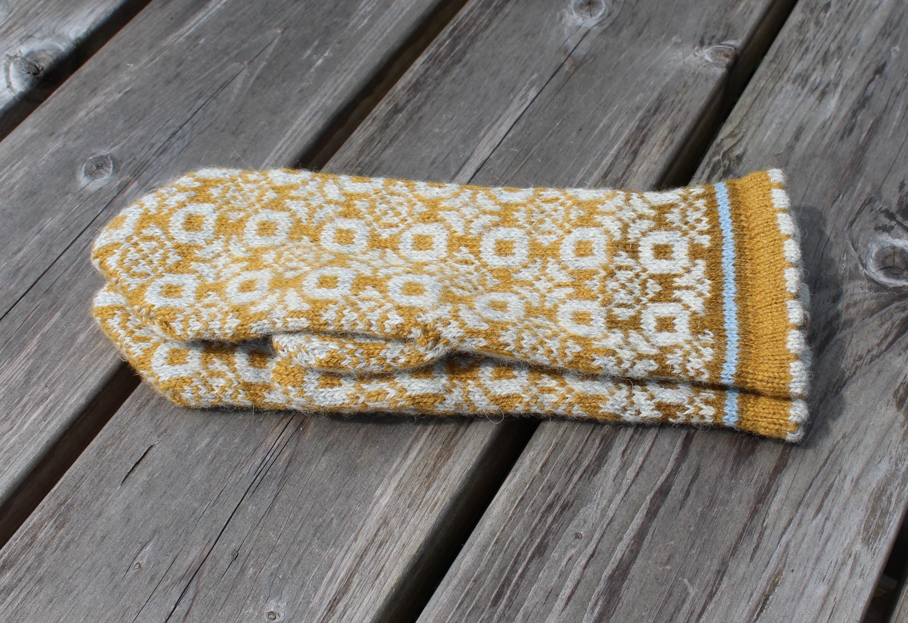 Knitted mitten with a geometric pattern on a wooden surface