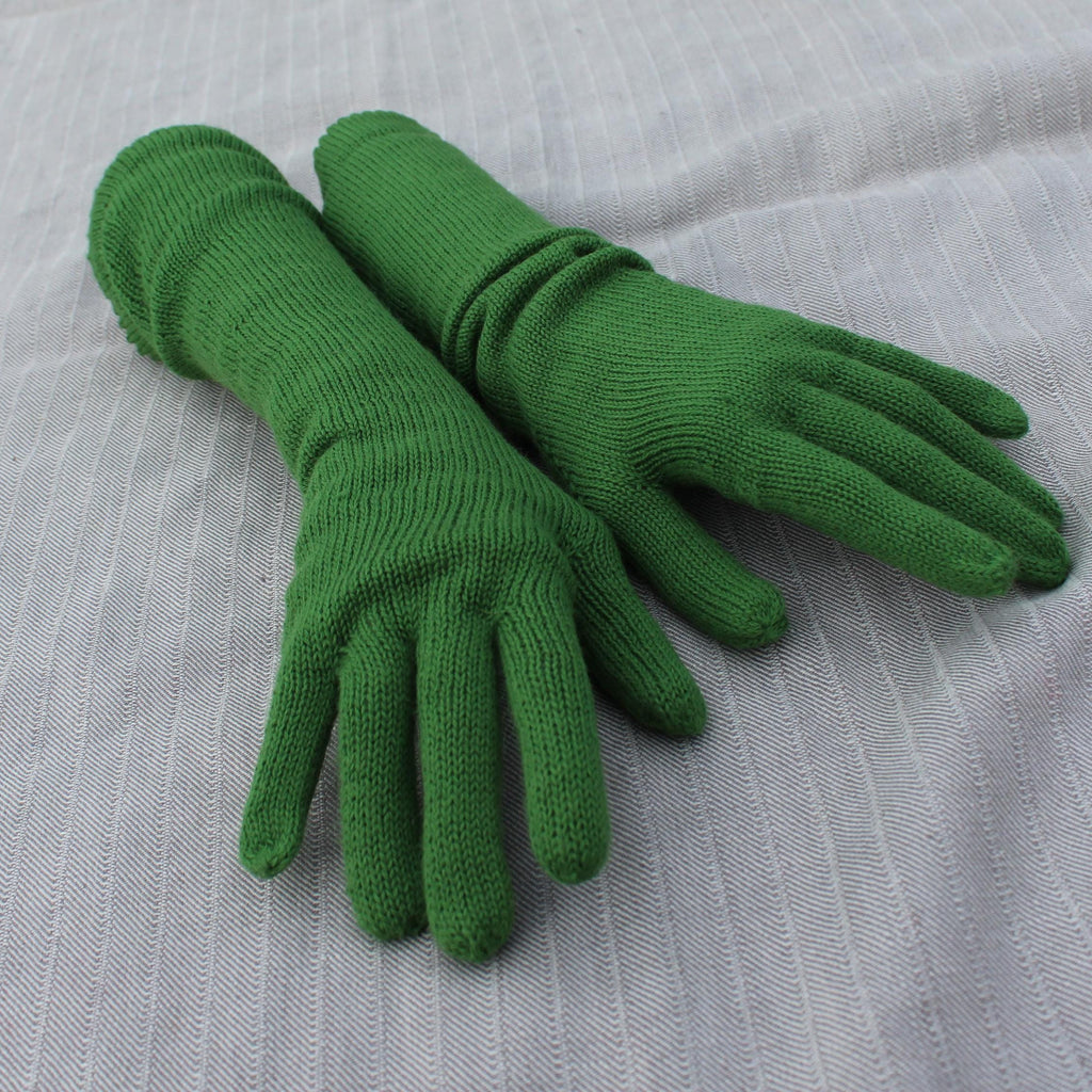 Pair of green gloves on a light gray fabric background