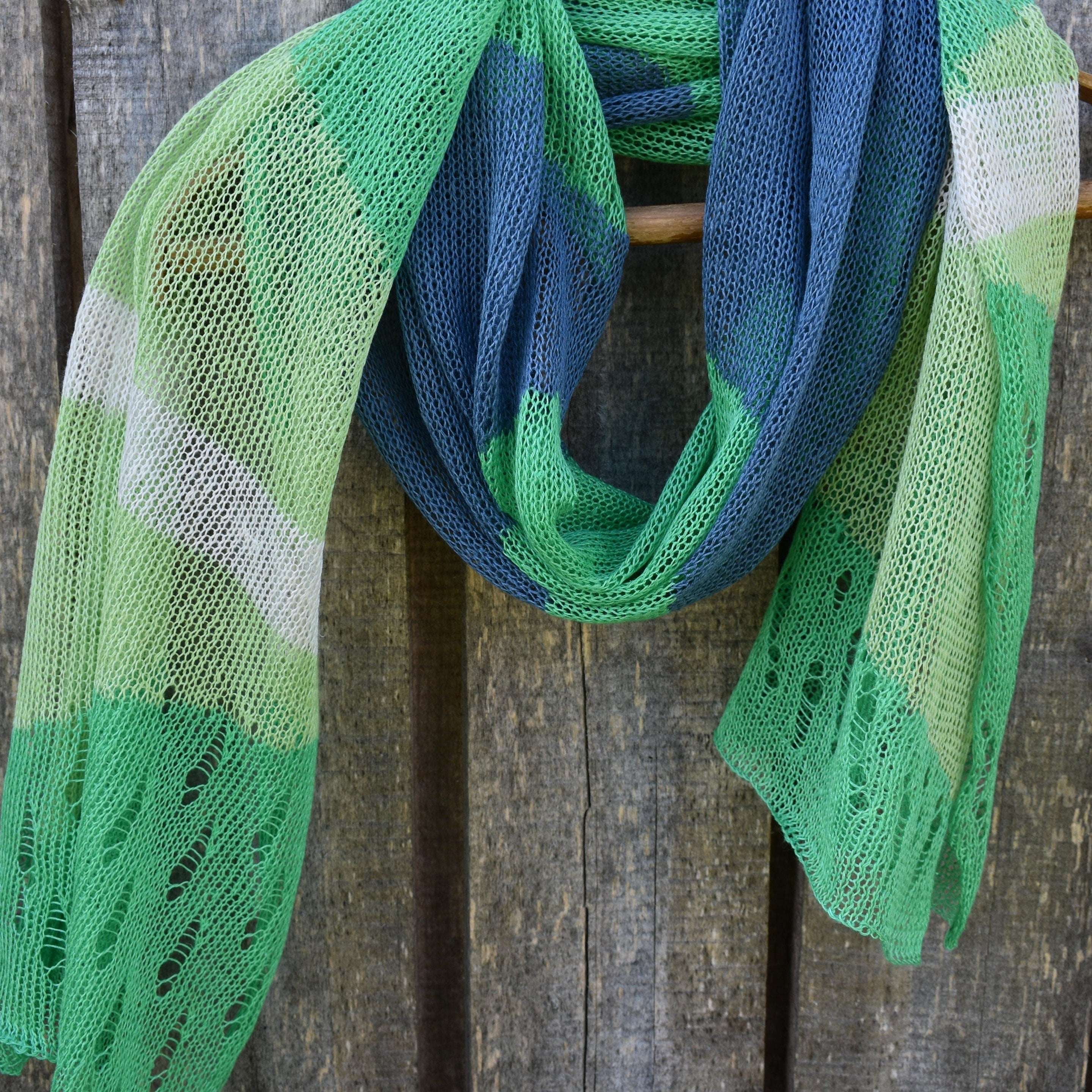 Green and blue knitted scarf on a wooden surface