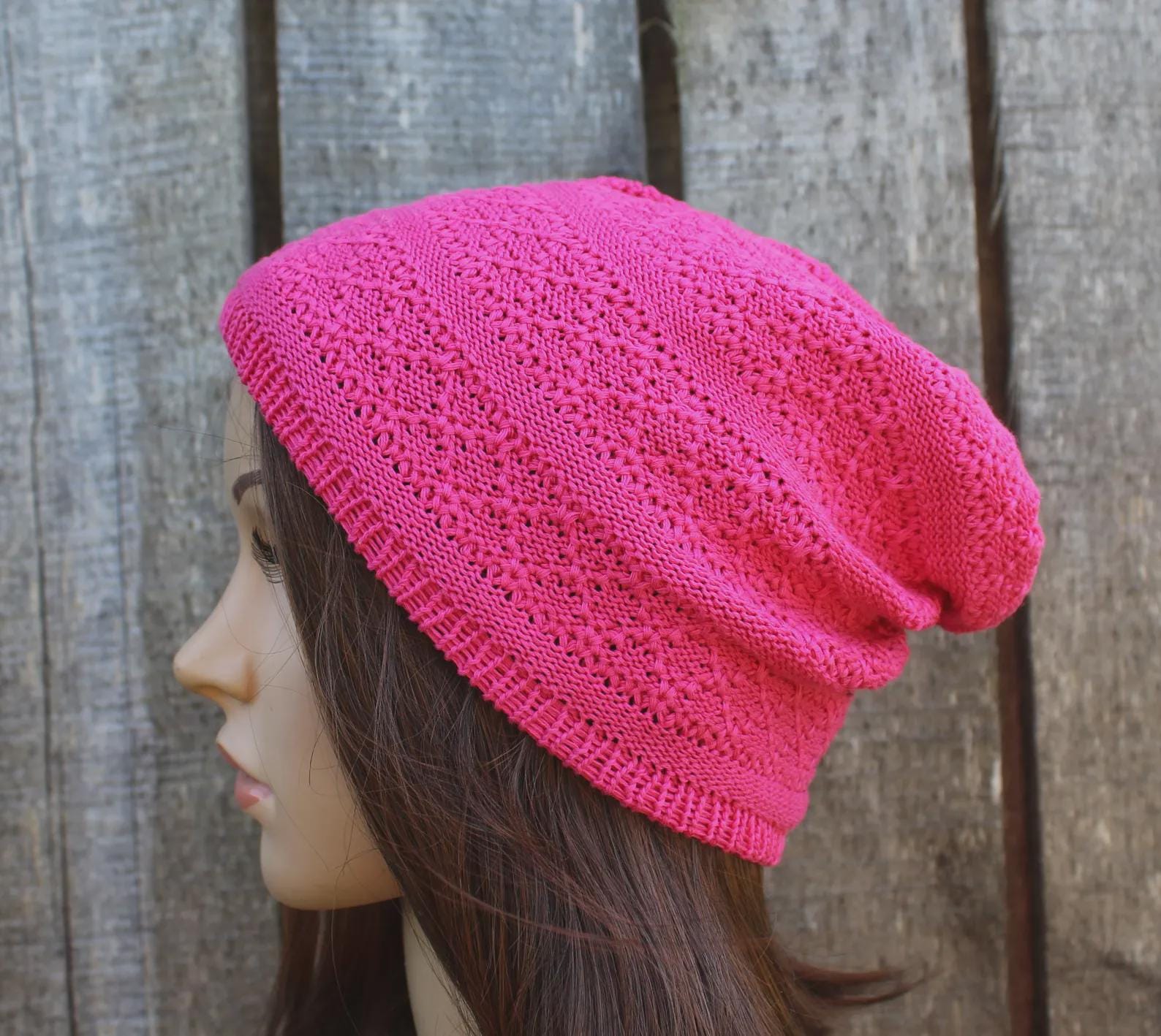 Pink knitted beanie on a mannequin head against a wooden background