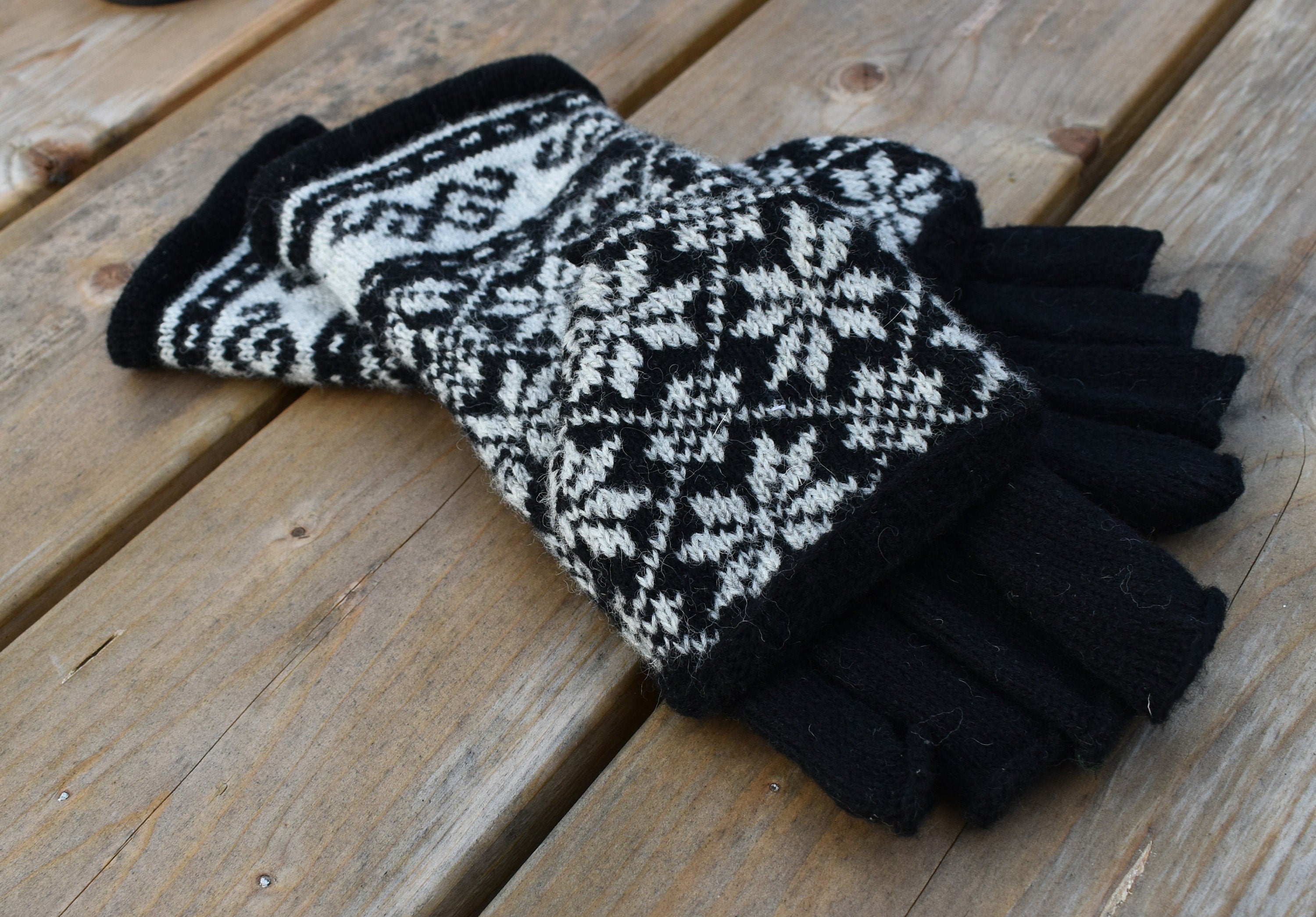 Pair of black and white patterned gloves on a wooden surface