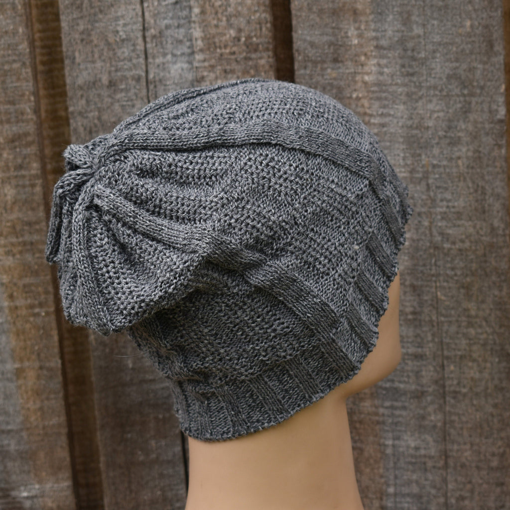 Gray knitted turban on a mannequin head against a wooden background