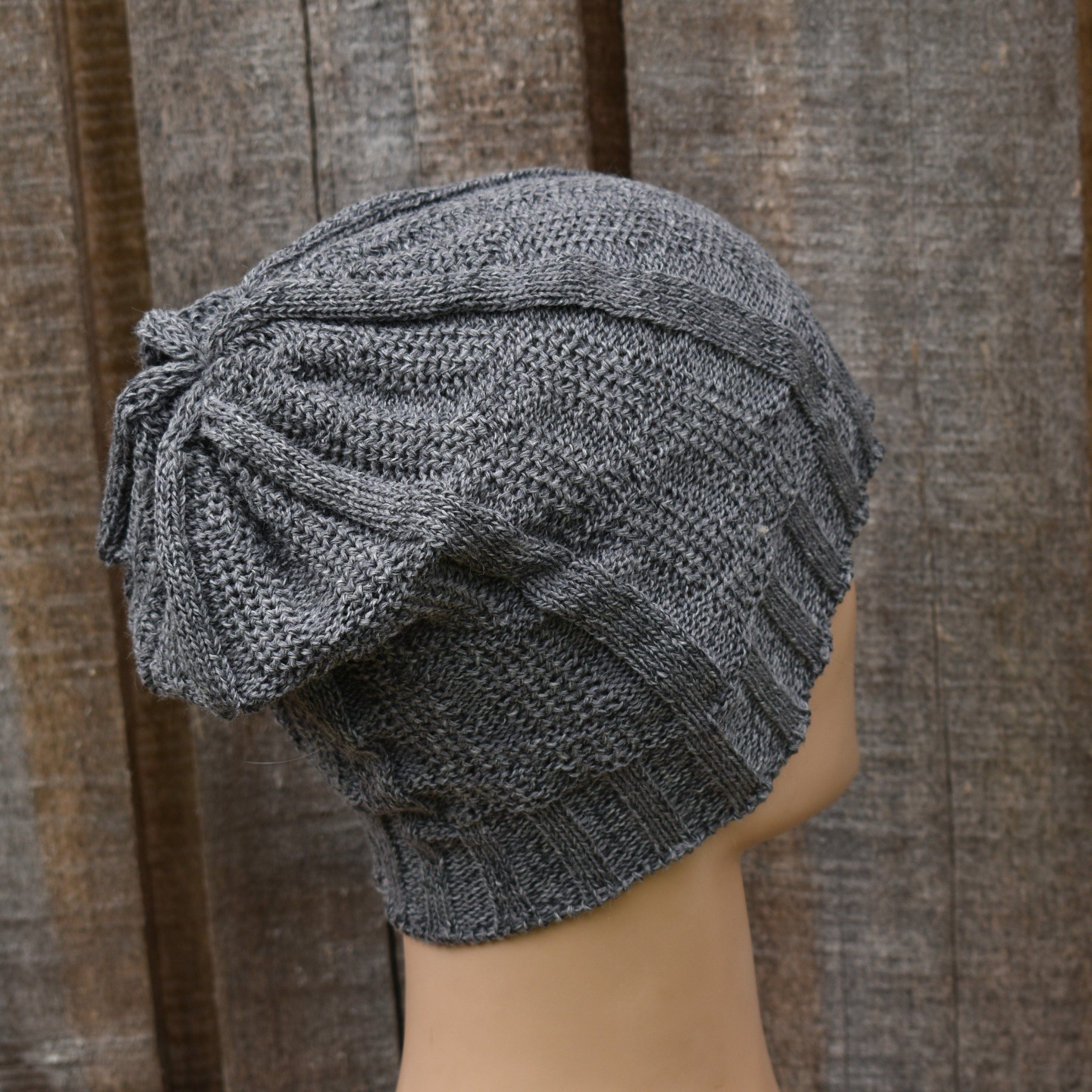 Gray knitted turban on a mannequin head against a wooden background