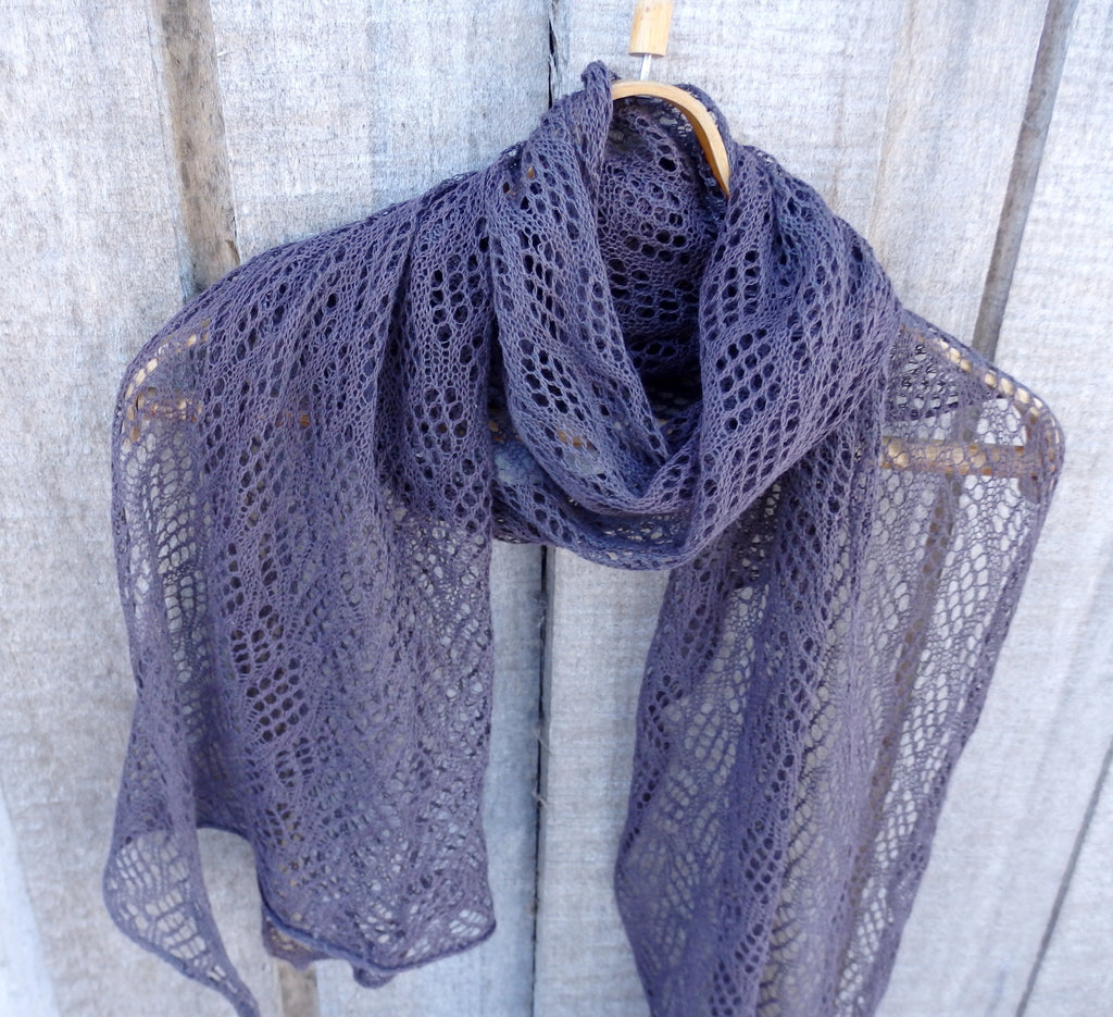 Lace shawl draped over a wooden hanger against a neutral background