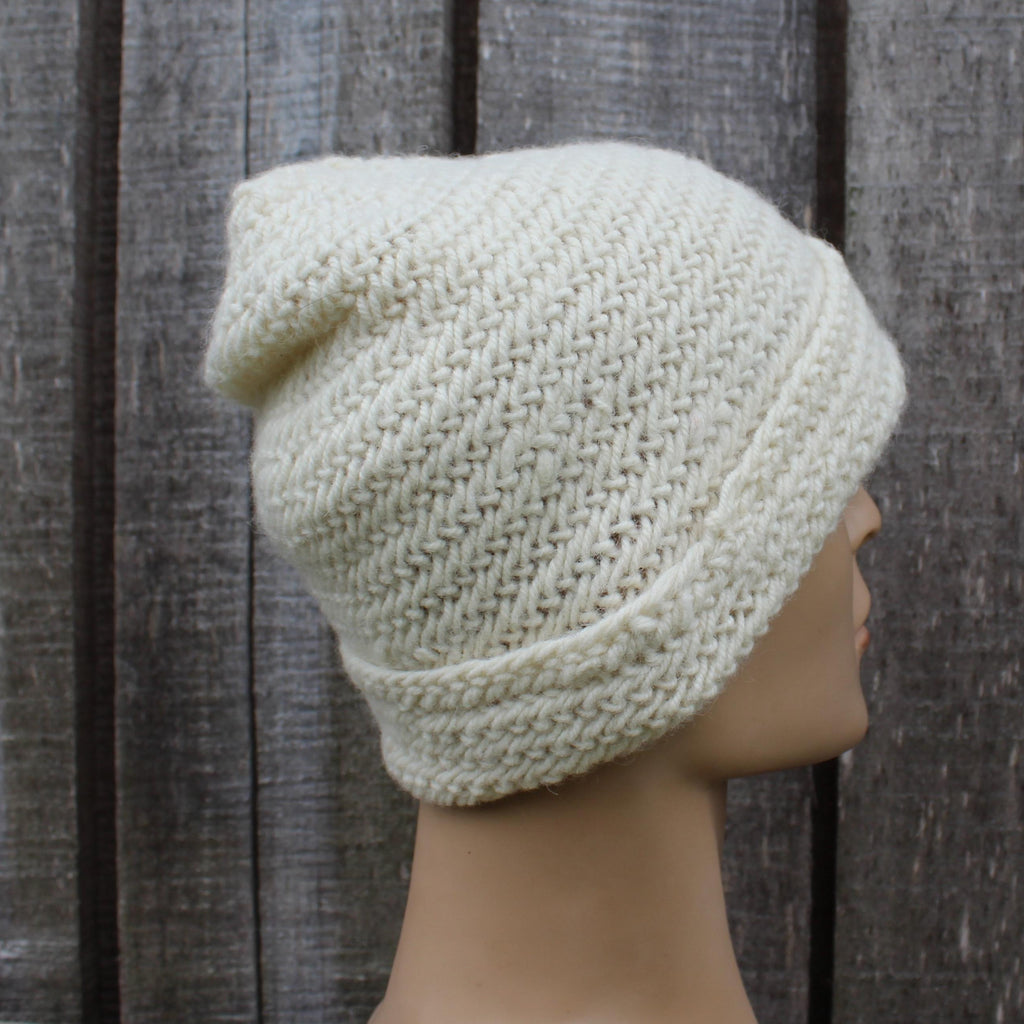 Knitted beige beanie on a mannequin head against a wooden background