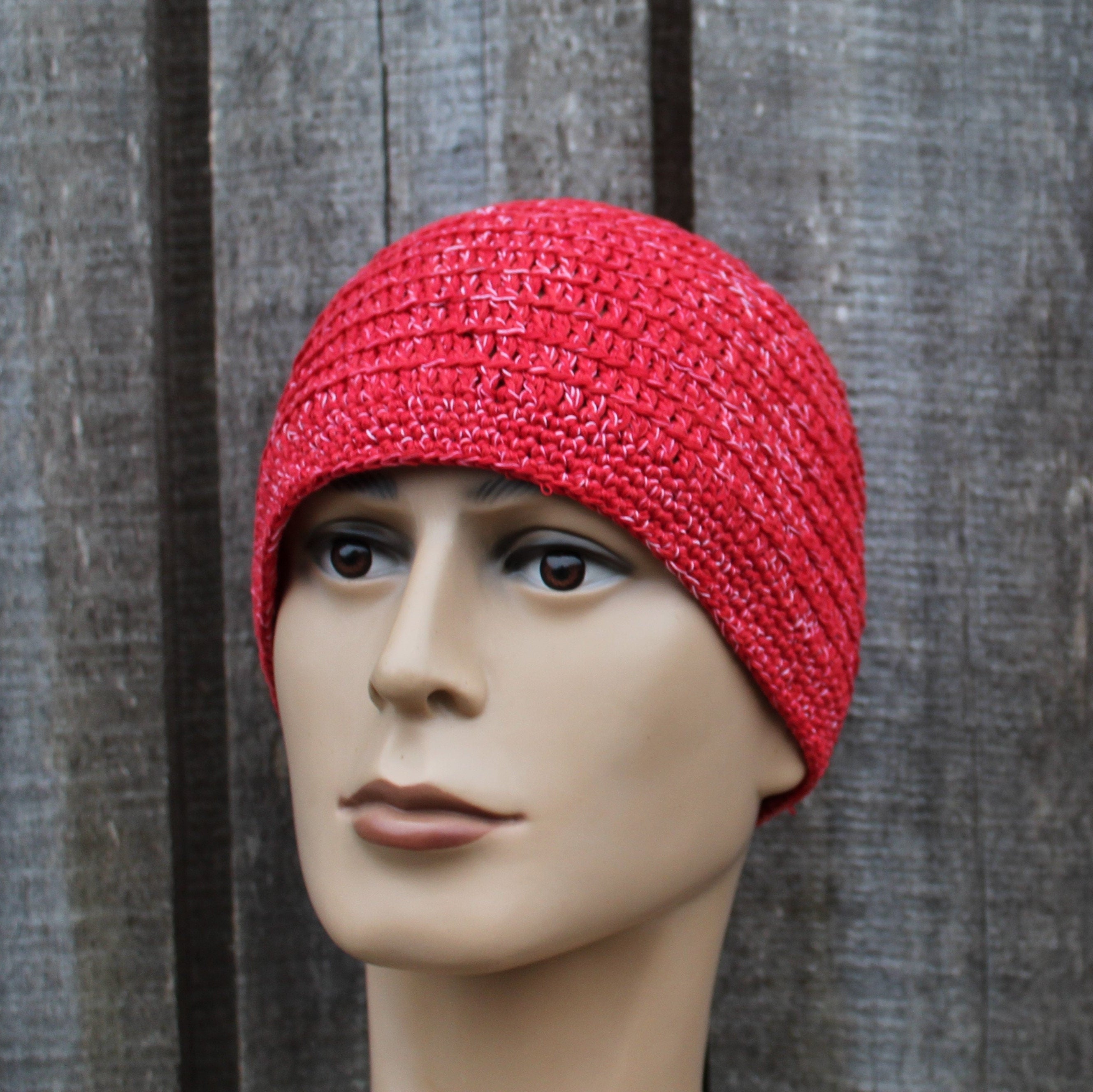 Red knitted beanie on a mannequin head against a wooden background