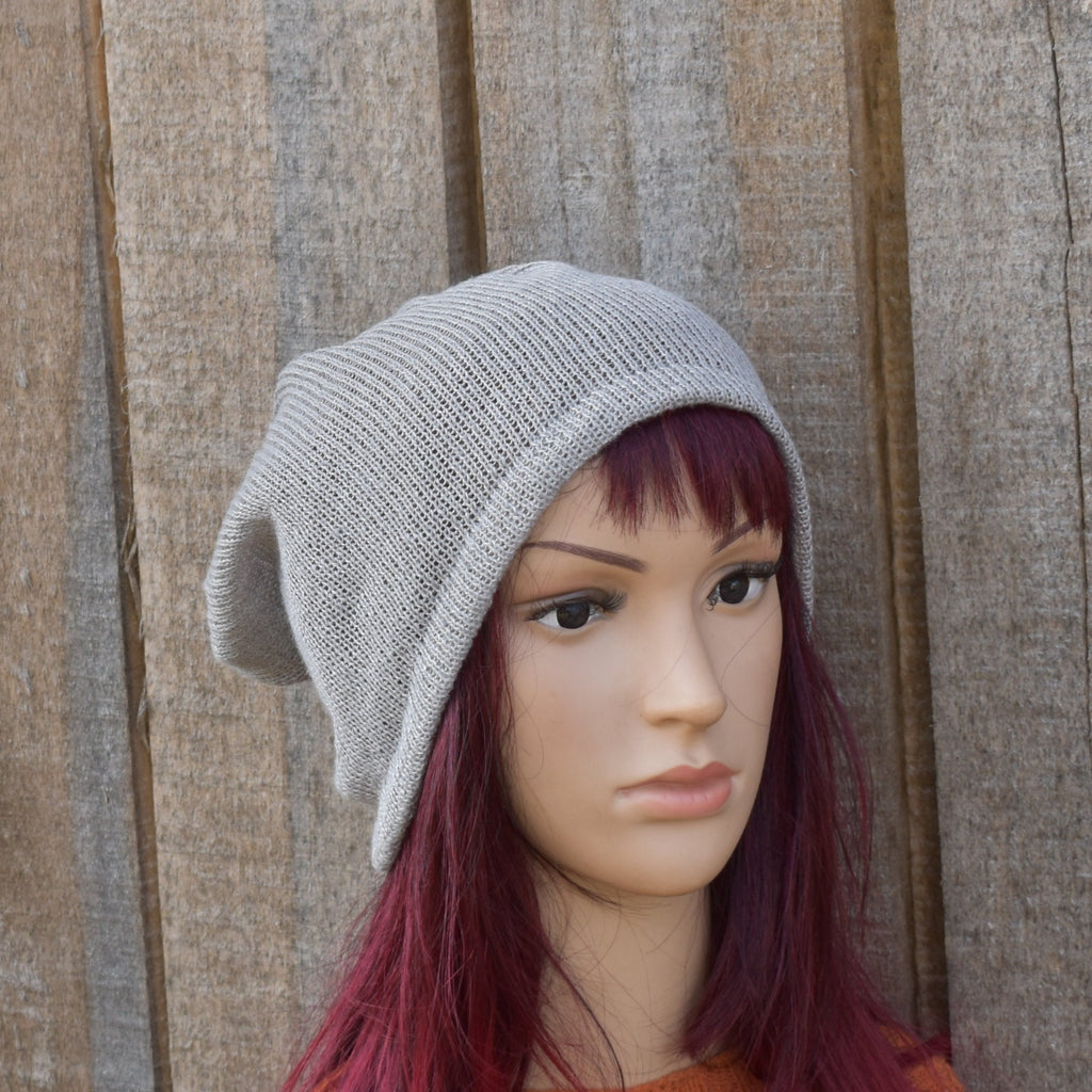 Mannequin head wearing a gray knit beanie against a wooden background