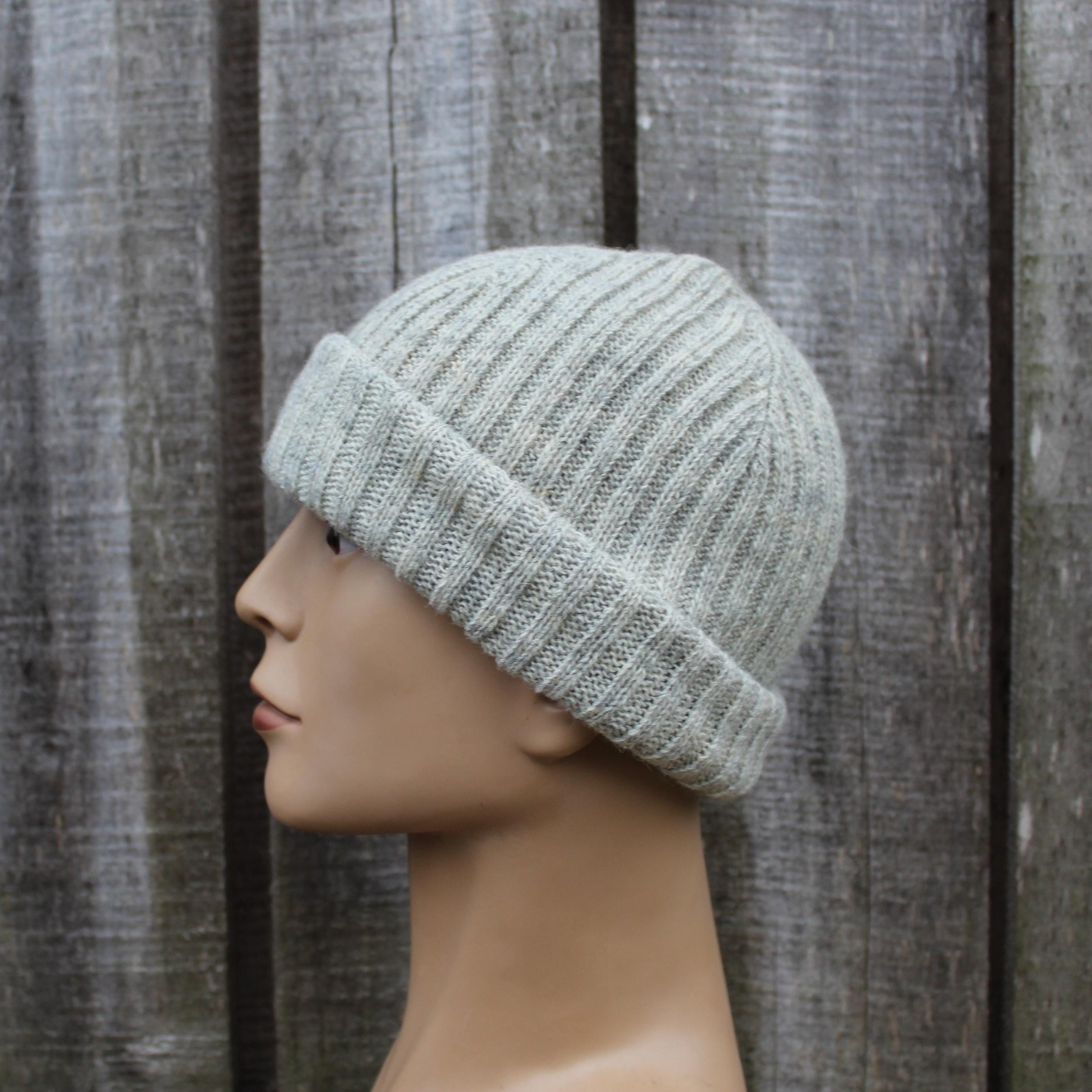 Knitted gray beanie on a mannequin head against a wooden background