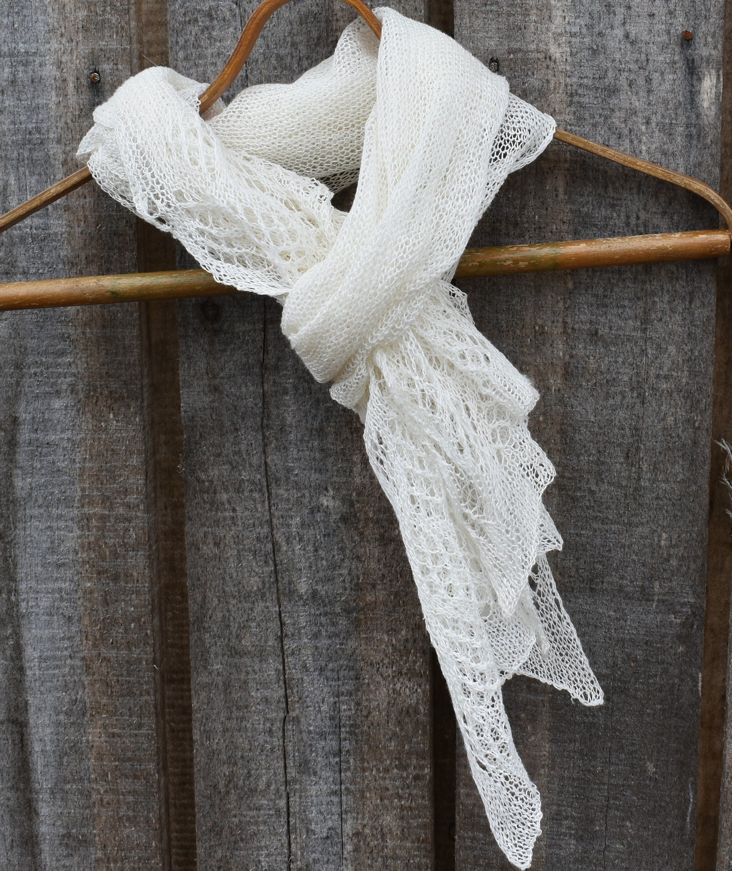 White lace scarf on a wooden hanger against a rustic wooden background