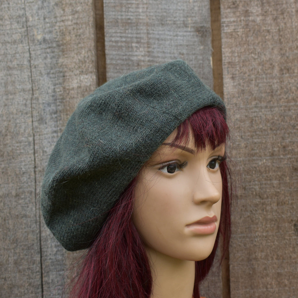 Mannequin head wearing a grey beret against a wooden panel background