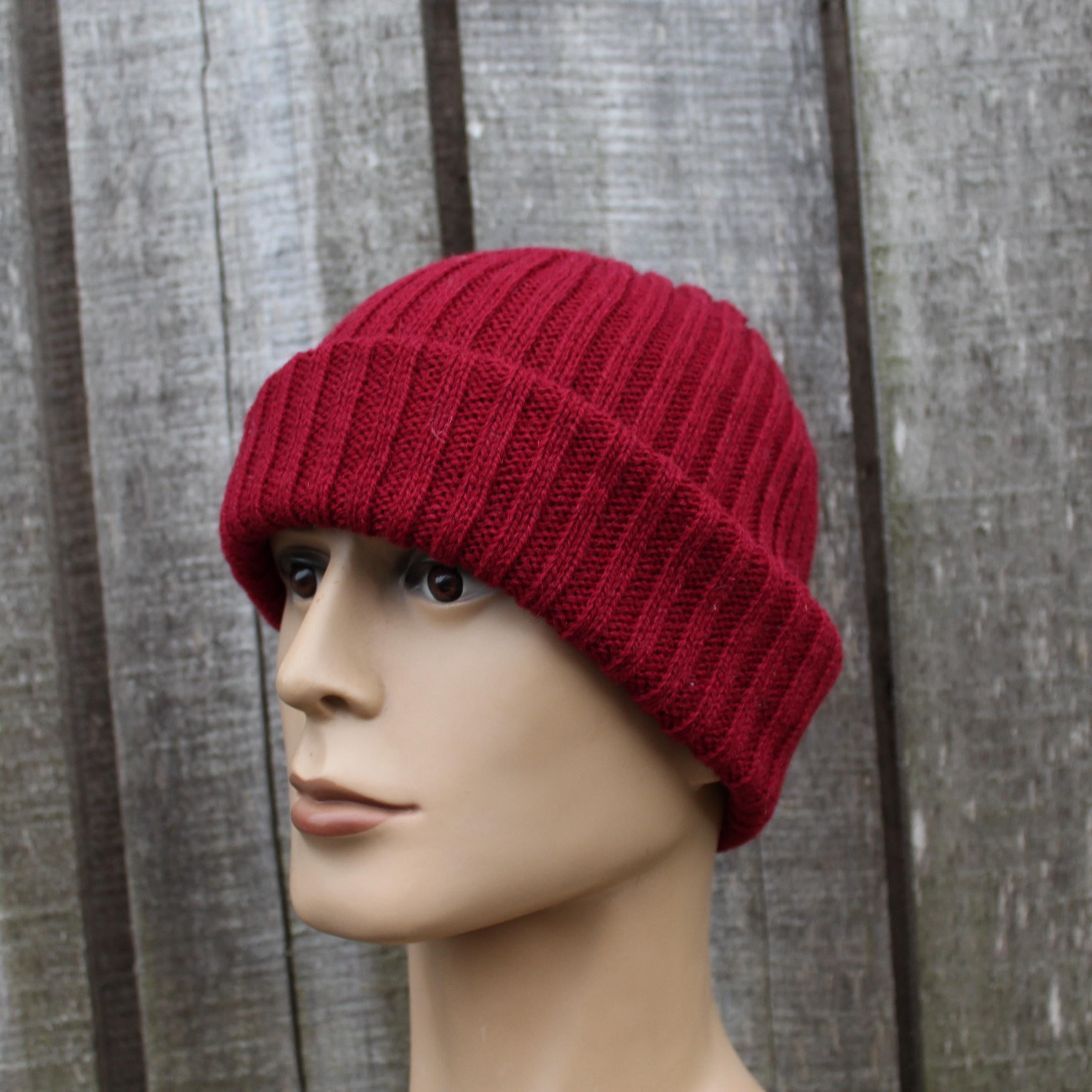 Red knitted beanie on a mannequin head against a wooden background