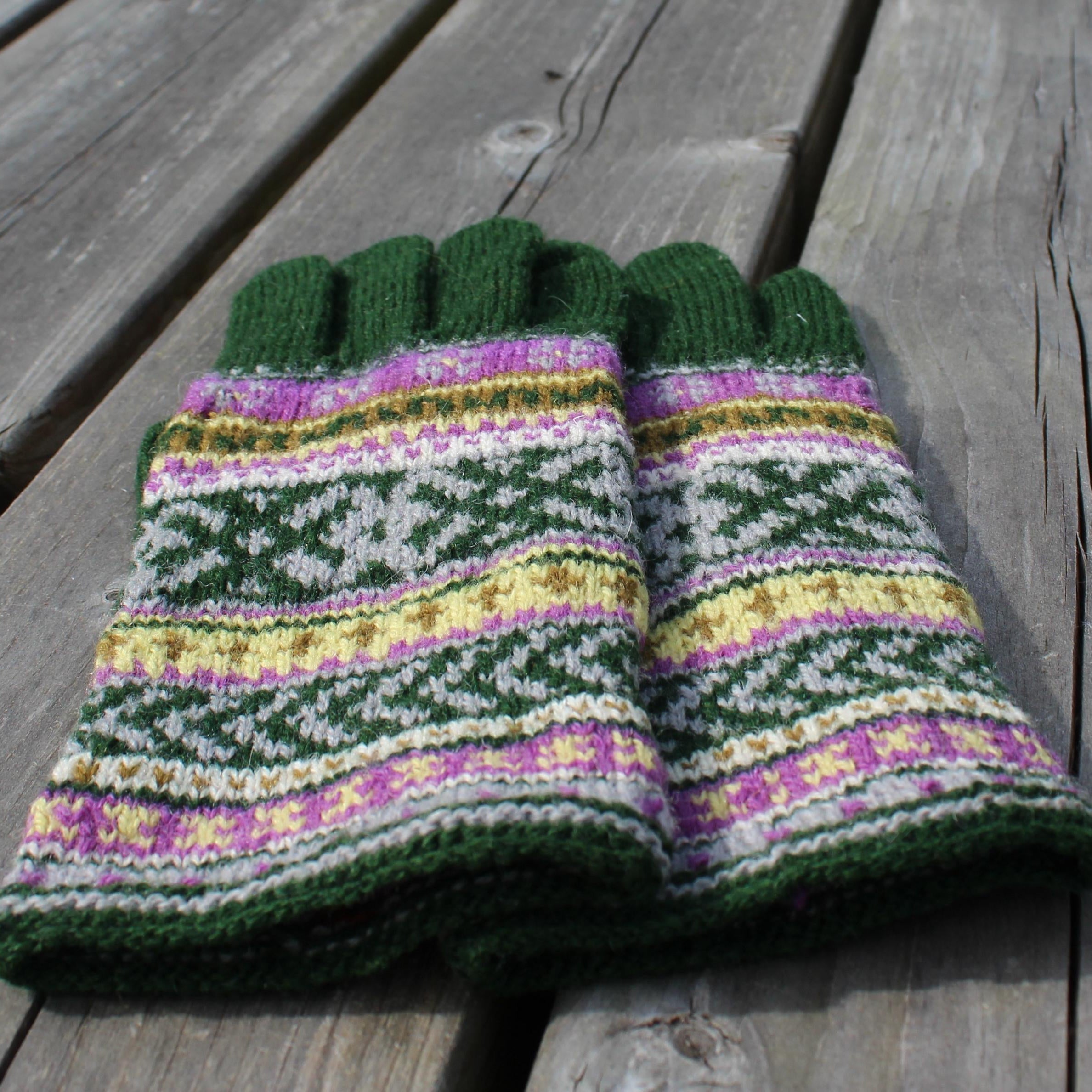 Knitted gloves with a colorful pattern on a wooden surface