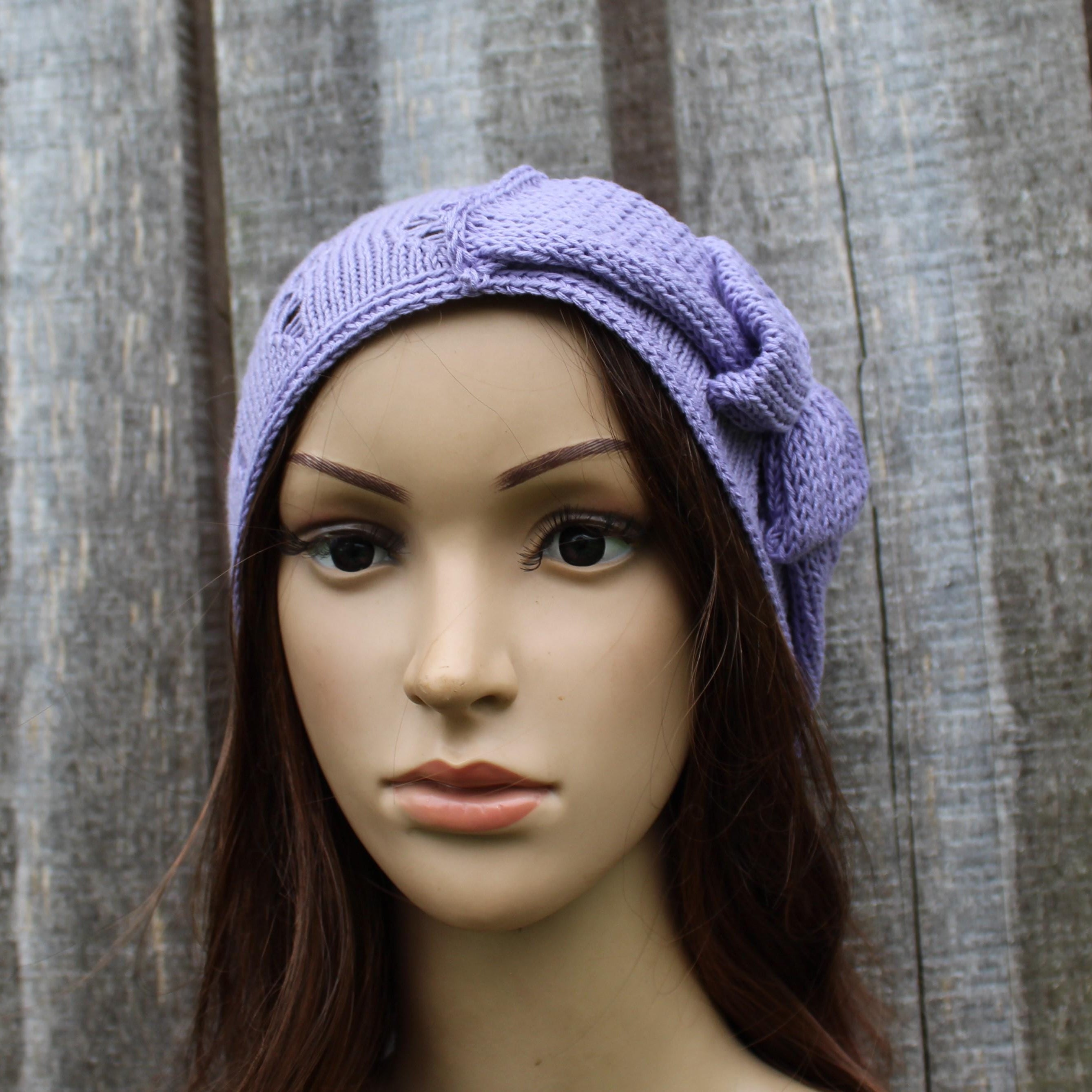 Mannequin head wearing a purple knitted headband against a wooden background