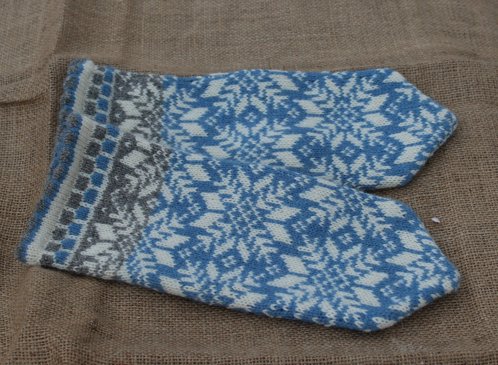 Pair of blue and gray patterned mittens on a brown fabric background