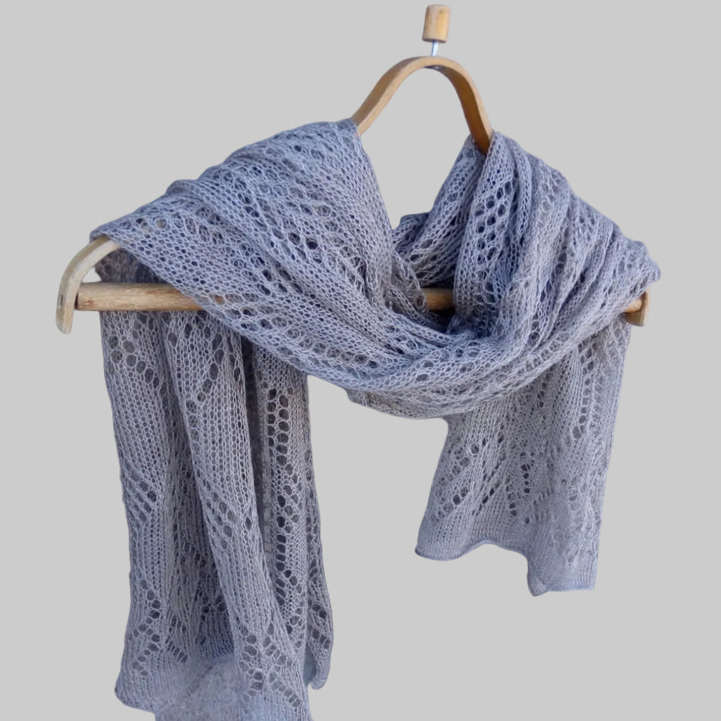 Knitted scarf on a wooden hanger against a wooden background