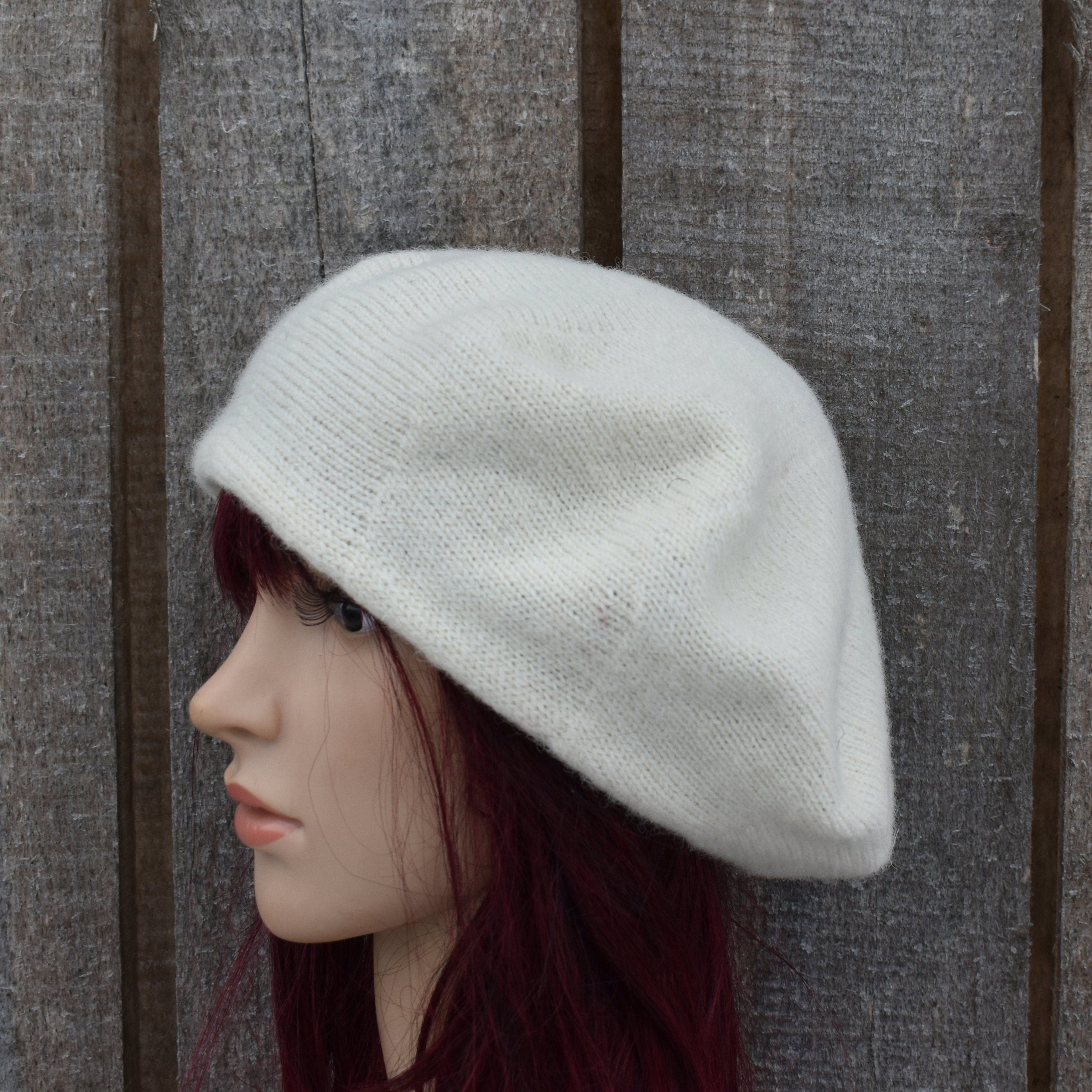 White knit beret on a mannequin head against a wooden background
