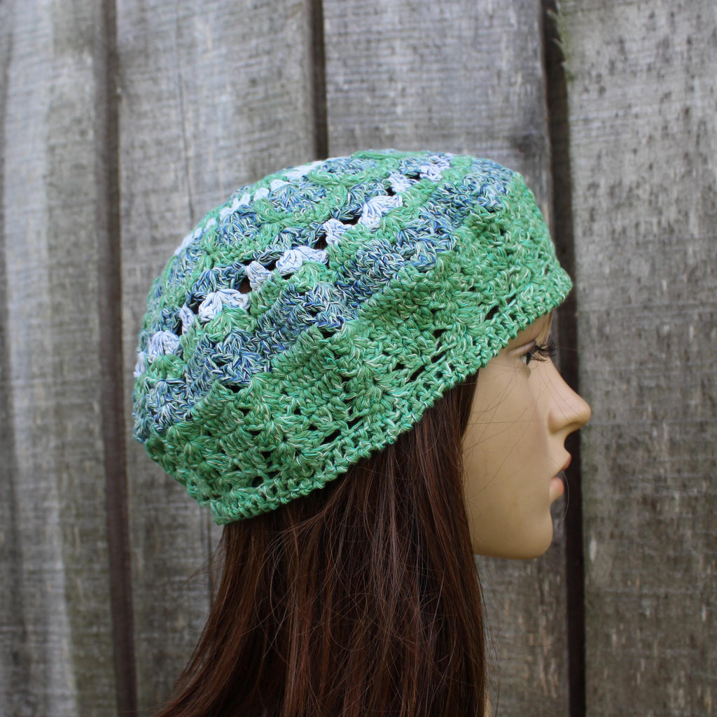 Green crocheted headband on a mannequin head against a wooden background