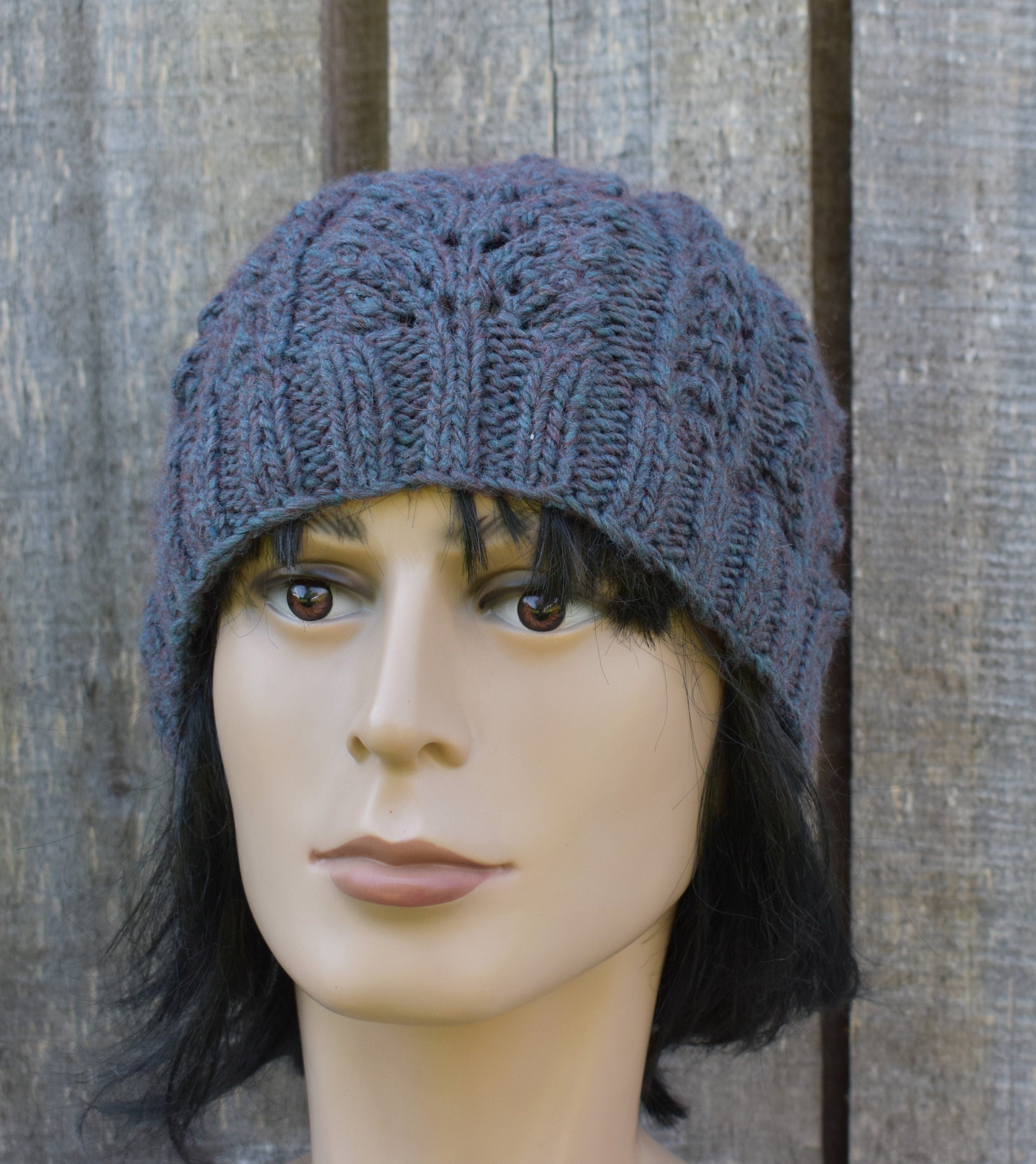 Mannequin head wearing a blue knitted hat against a wooden background
