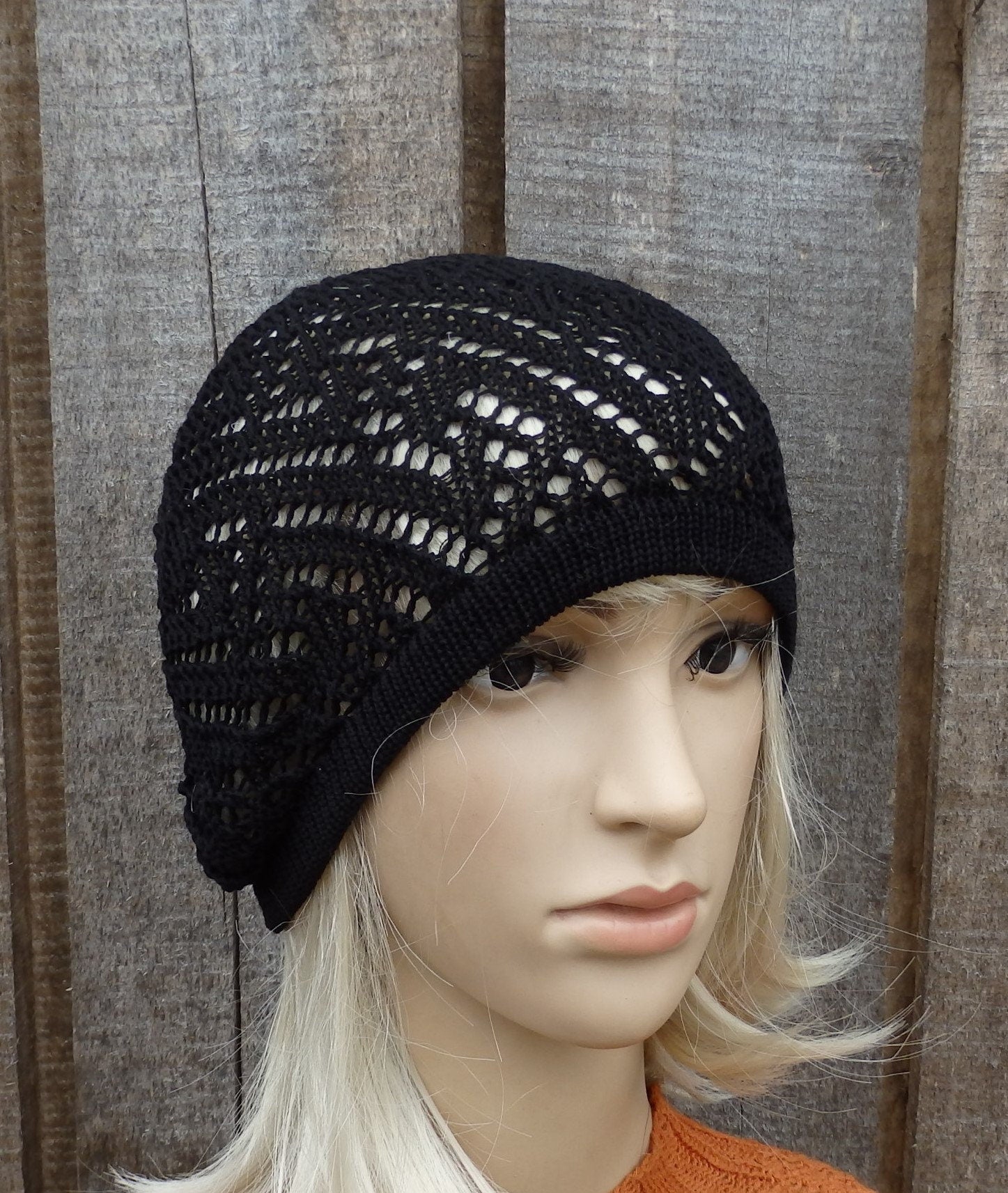 Black knit beanie on a mannequin head against a wooden panel background