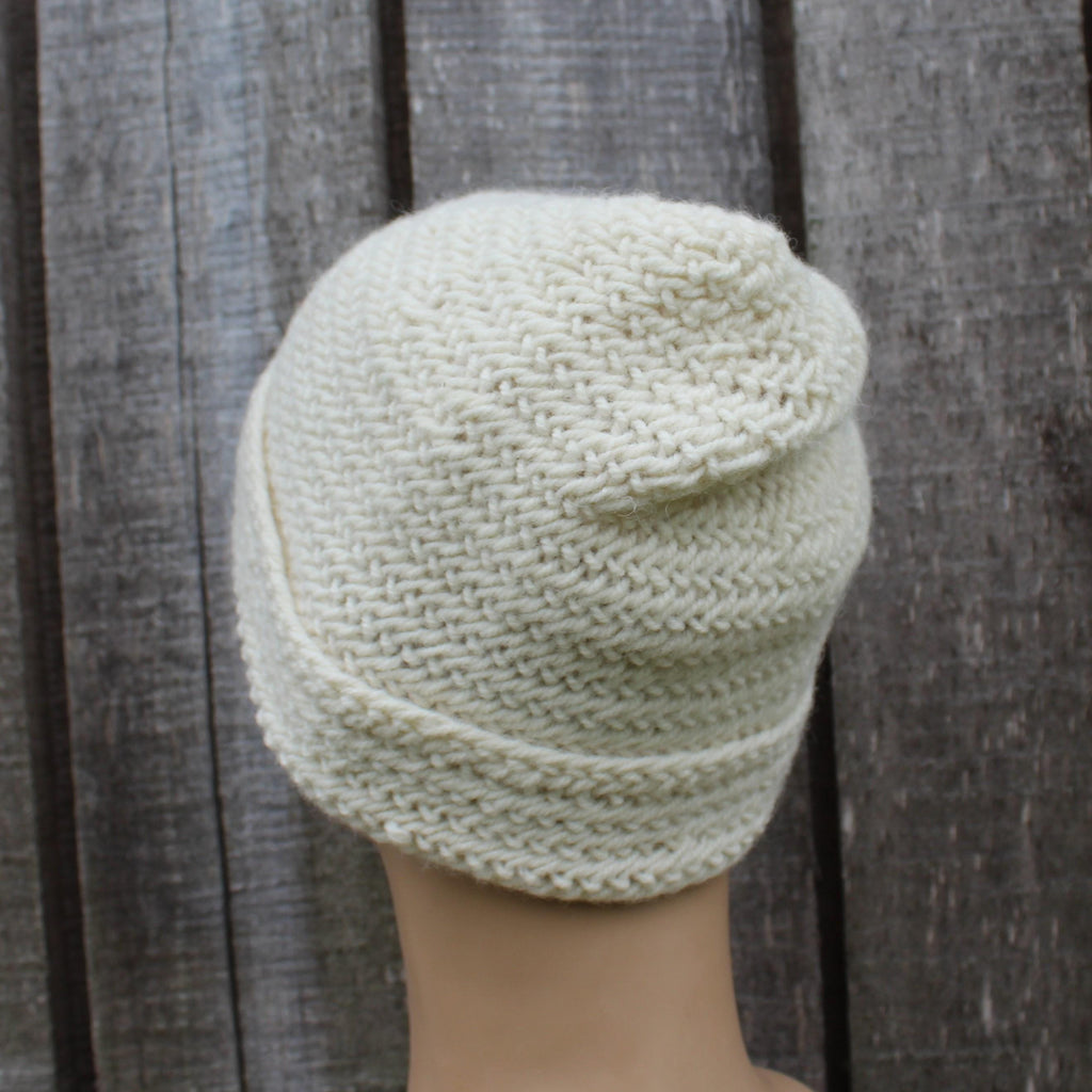 White wool beanie on a mannequin head against a wooden background