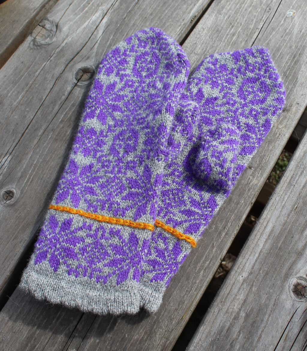 Purple and gray patterned mitten on a wooden surface