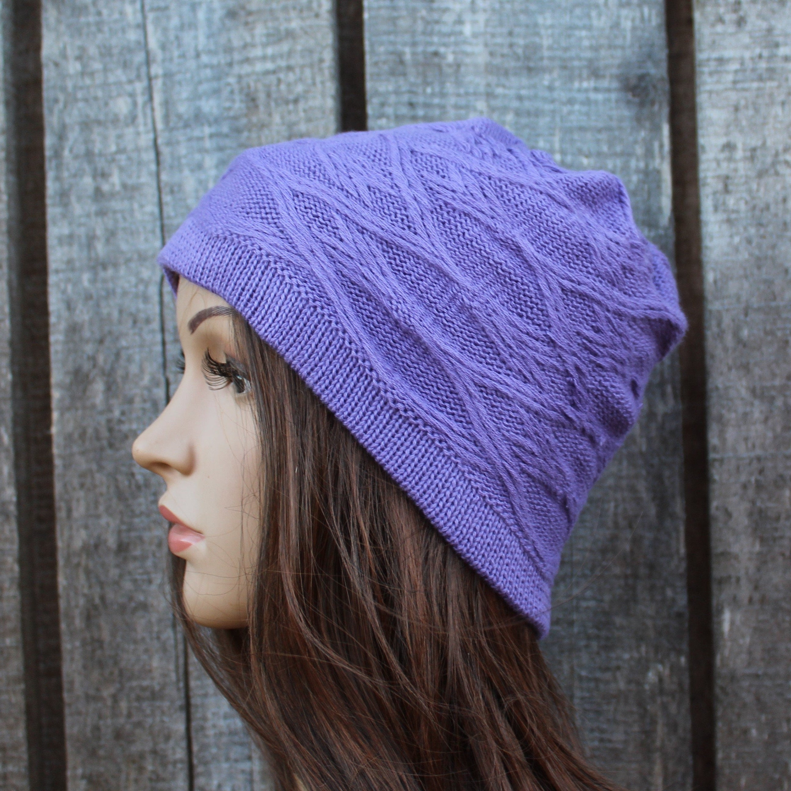 Person wearing a purple knitted beanie against a wooden background