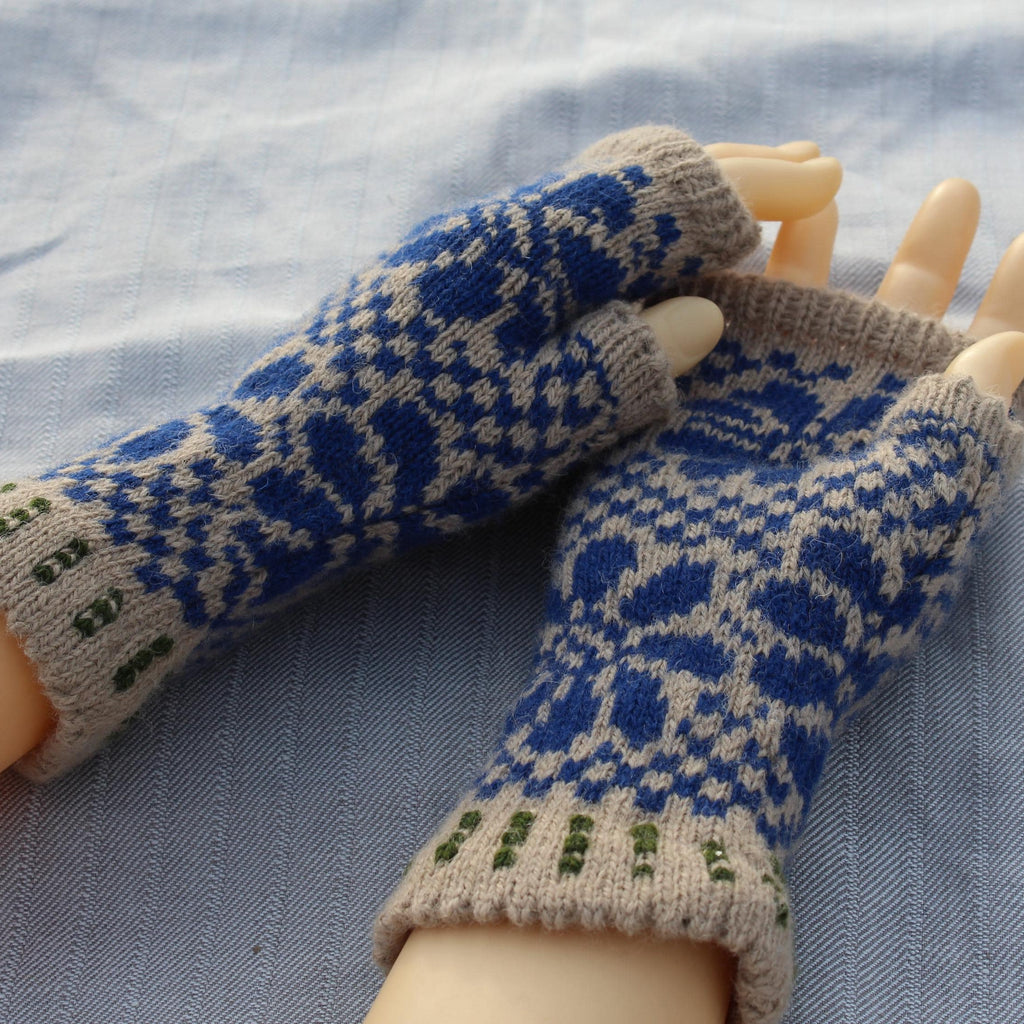 Pair of blue and beige patterned fingerless gloves on a mannequin arm against a light blue fabric background.