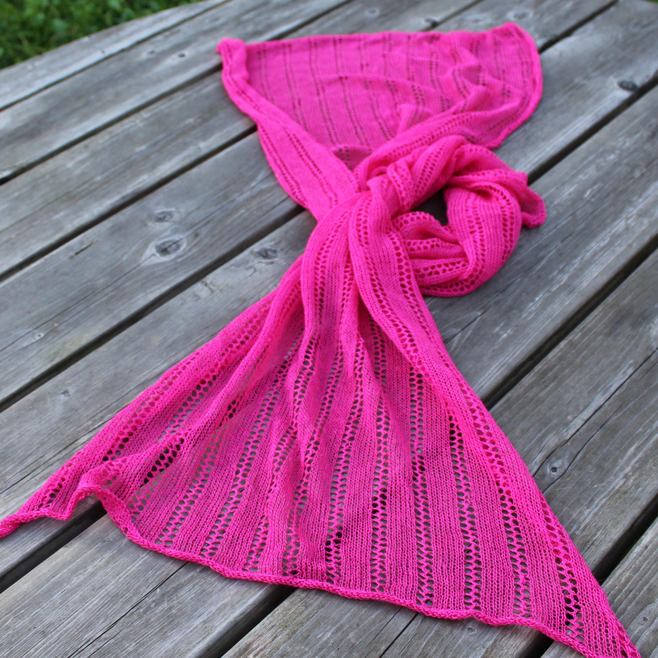 Pink knitted scarf on a wooden surface
