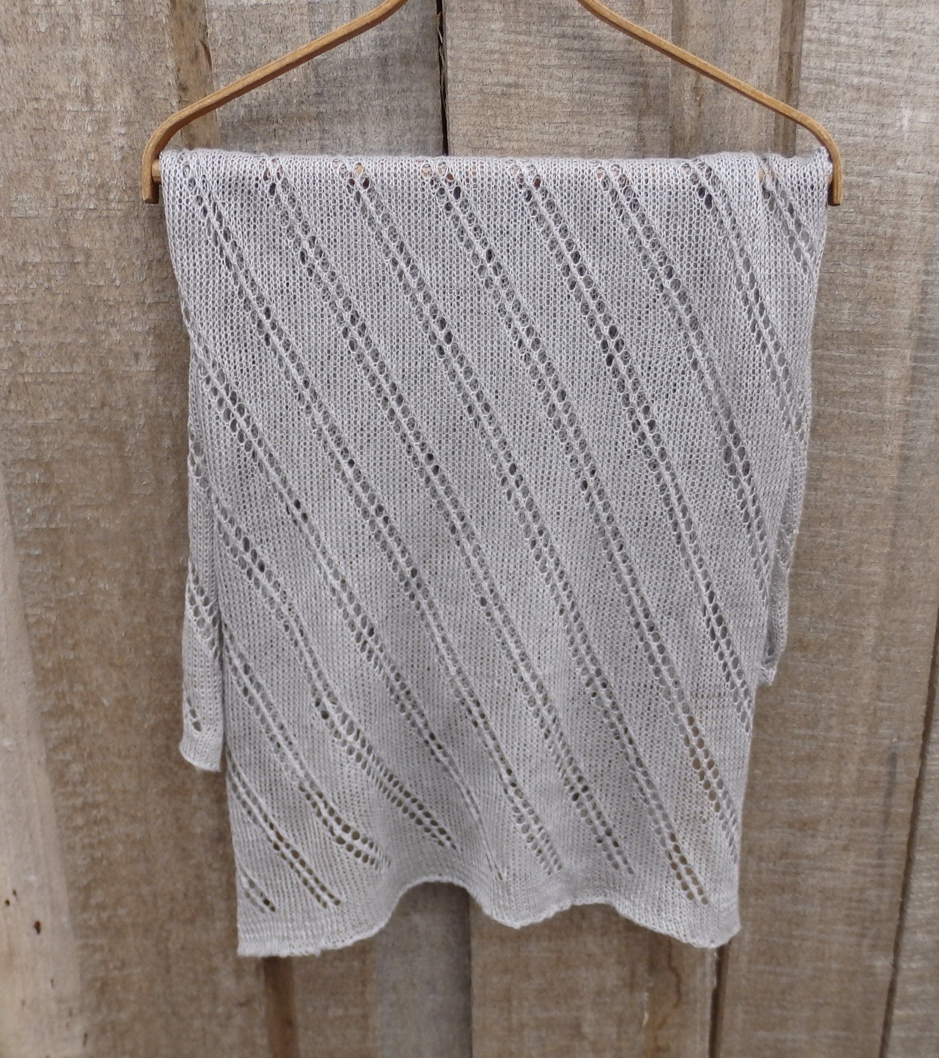 Knitted gray blanket on a wooden hanger against a wooden background