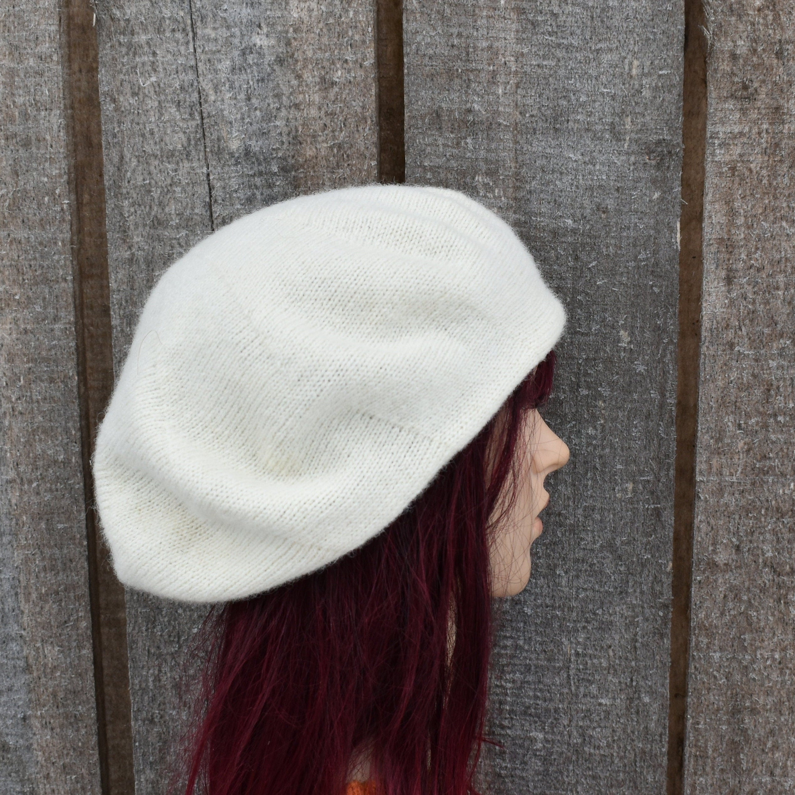 Person wearing a white knit cap against a wooden background