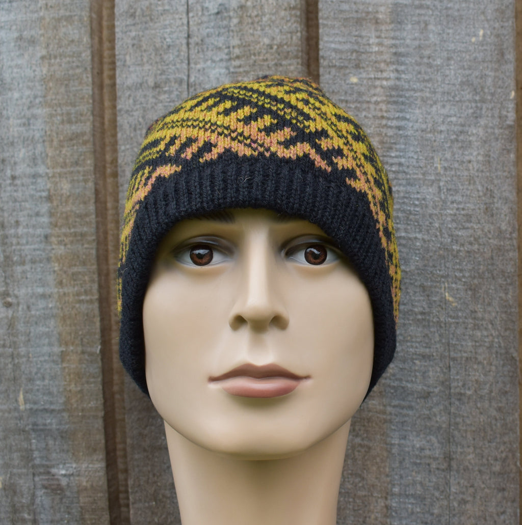 Knitted beanie with black and yellow pattern on a mannequin head against a wooden background