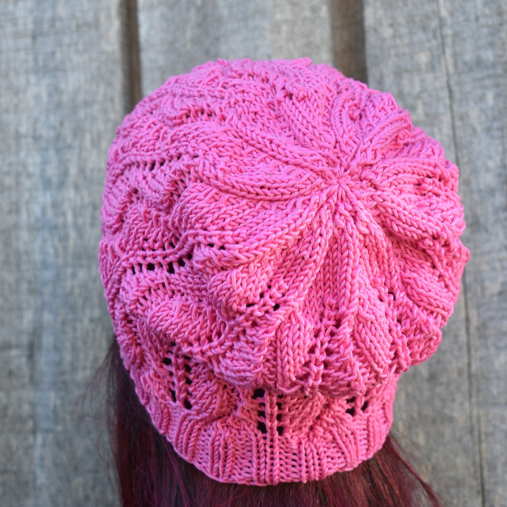 Pink knitted beanie on a person with a wooden background