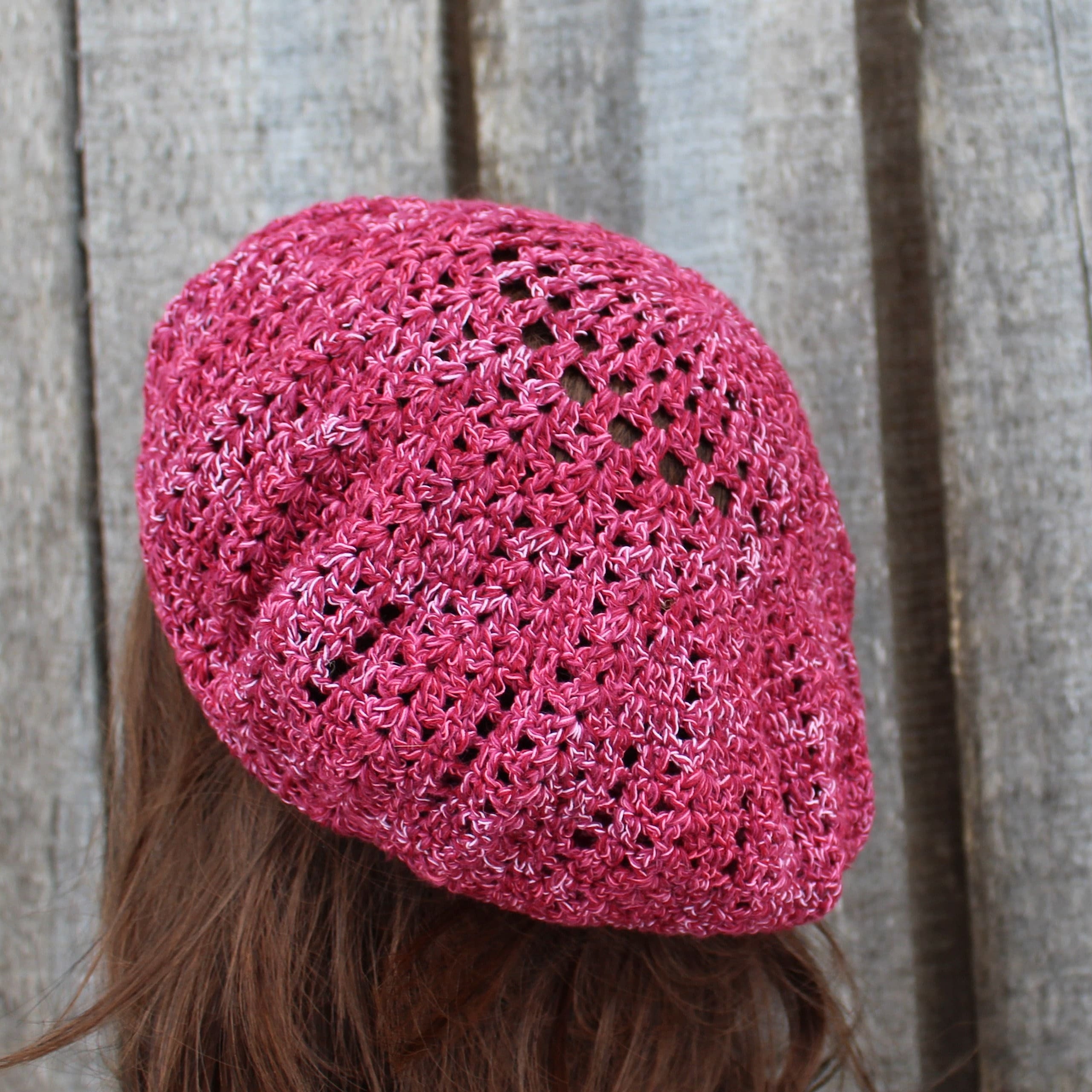 Pink knitted beanie on a person against a wooden background