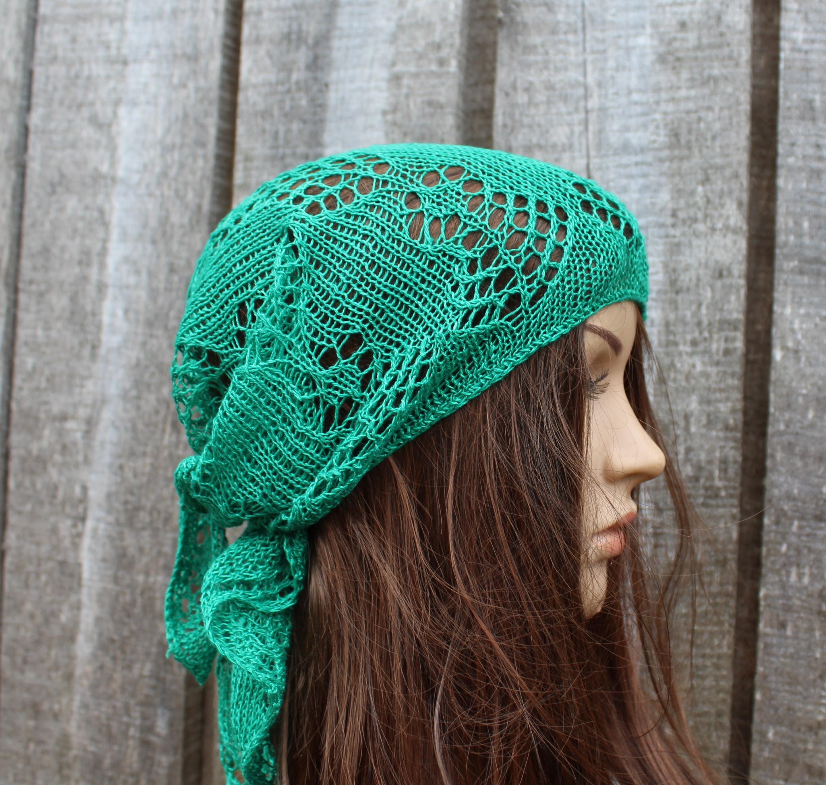 Green knitted headscarf worn by a person against a wooden background