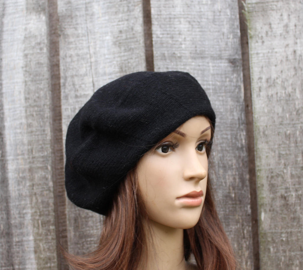 Black beret on a mannequin head against a wooden panel background
