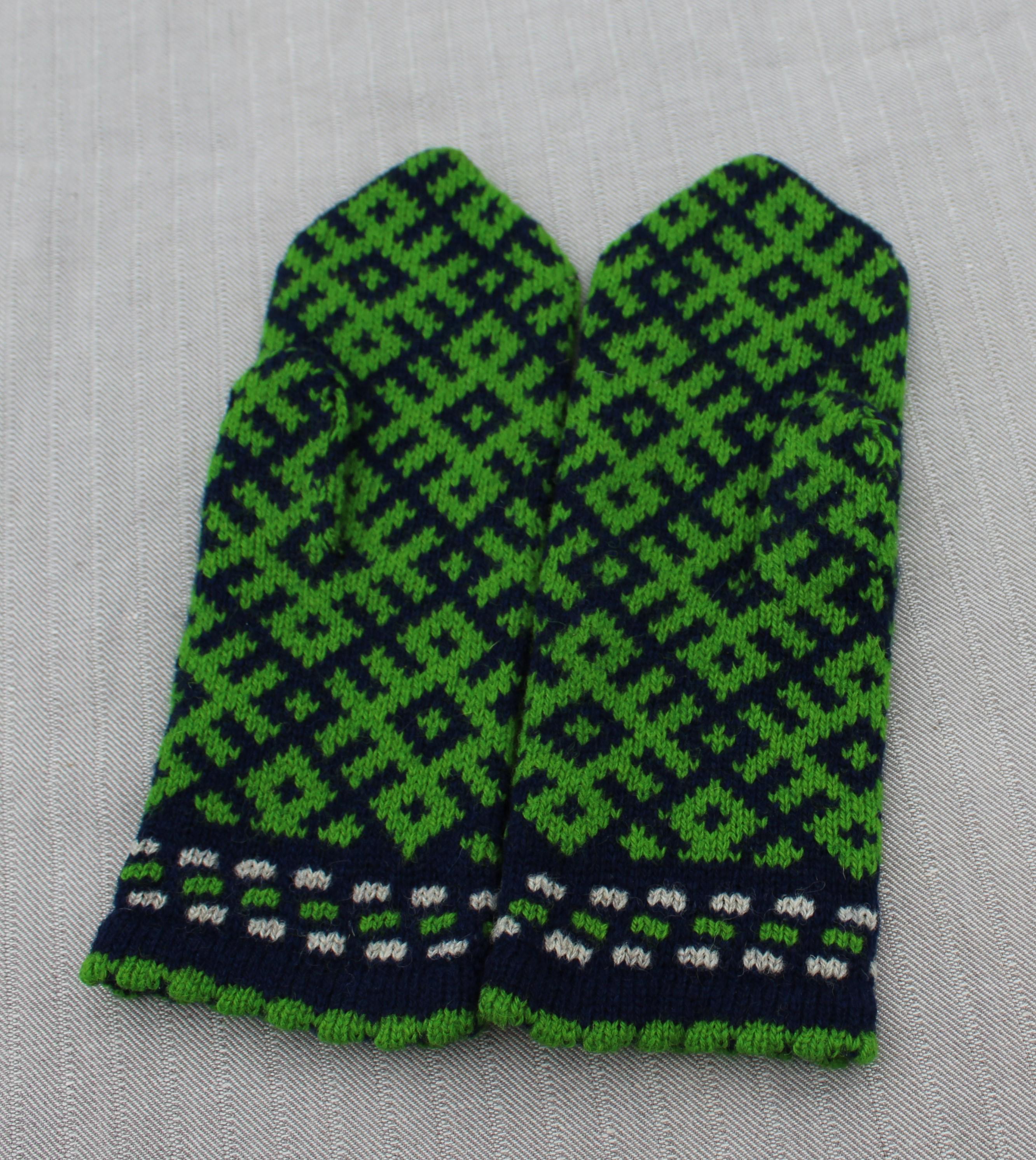 Pair of green and navy patterned mittens on a gray background