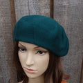 Teal beret on a mannequin head against a wooden background