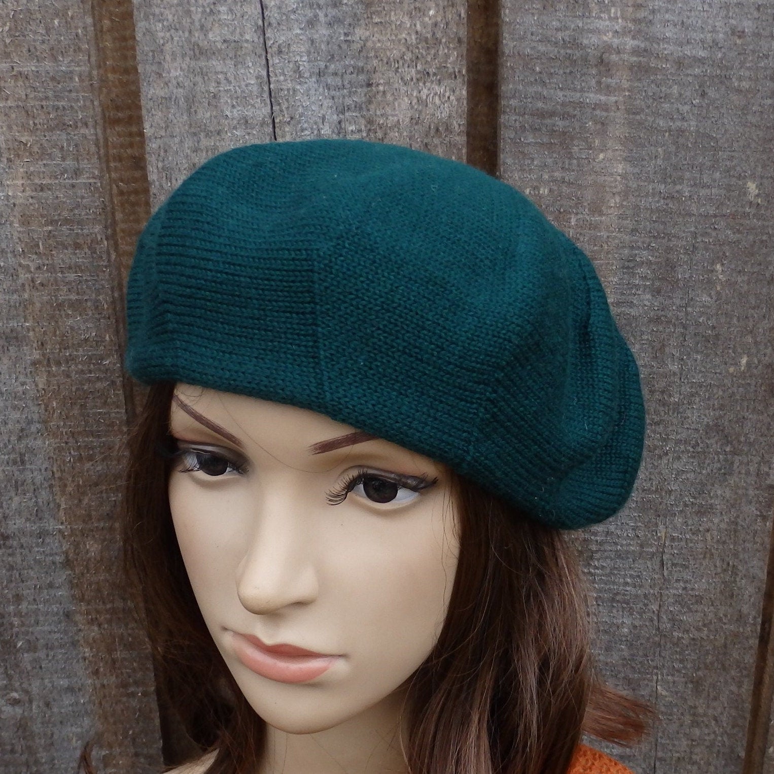 Teal beret on a mannequin head against a wooden background