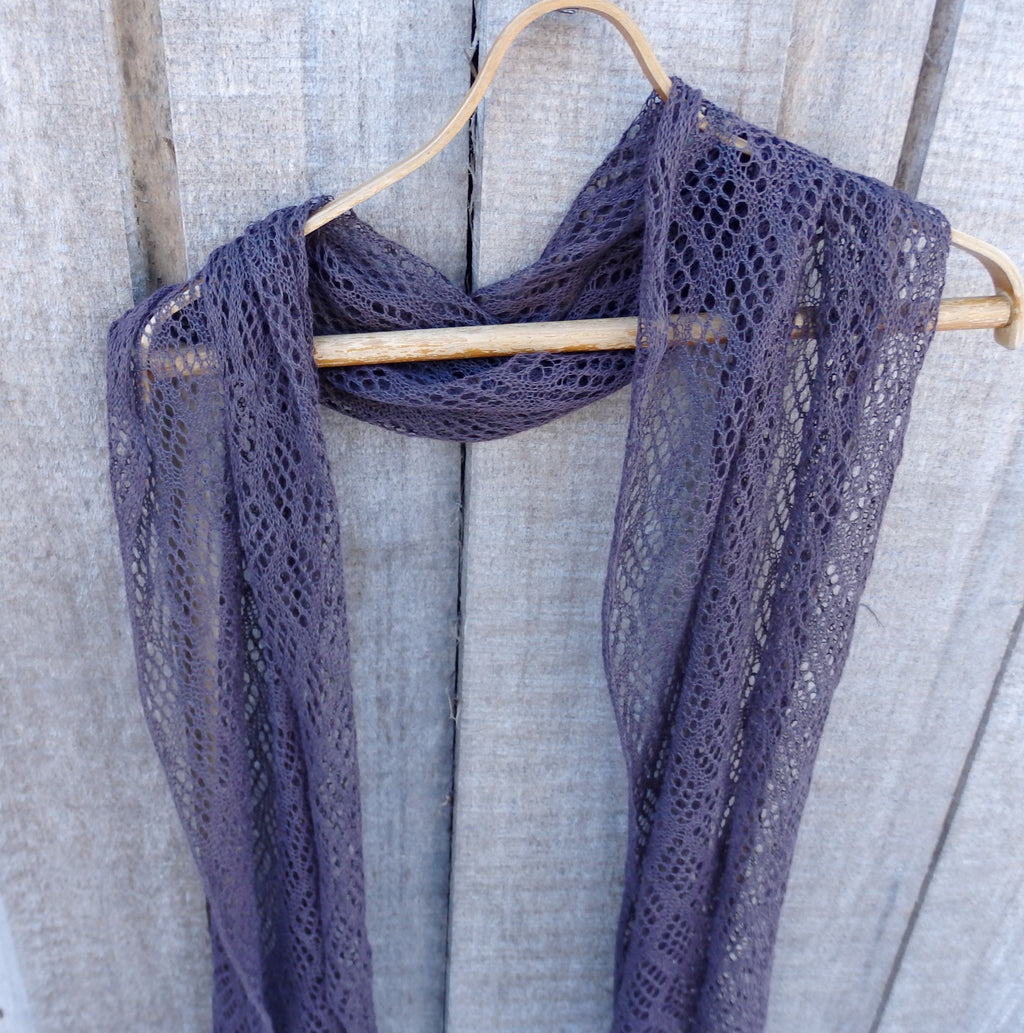 Purple lace scarf on a wooden hanger against a wooden background